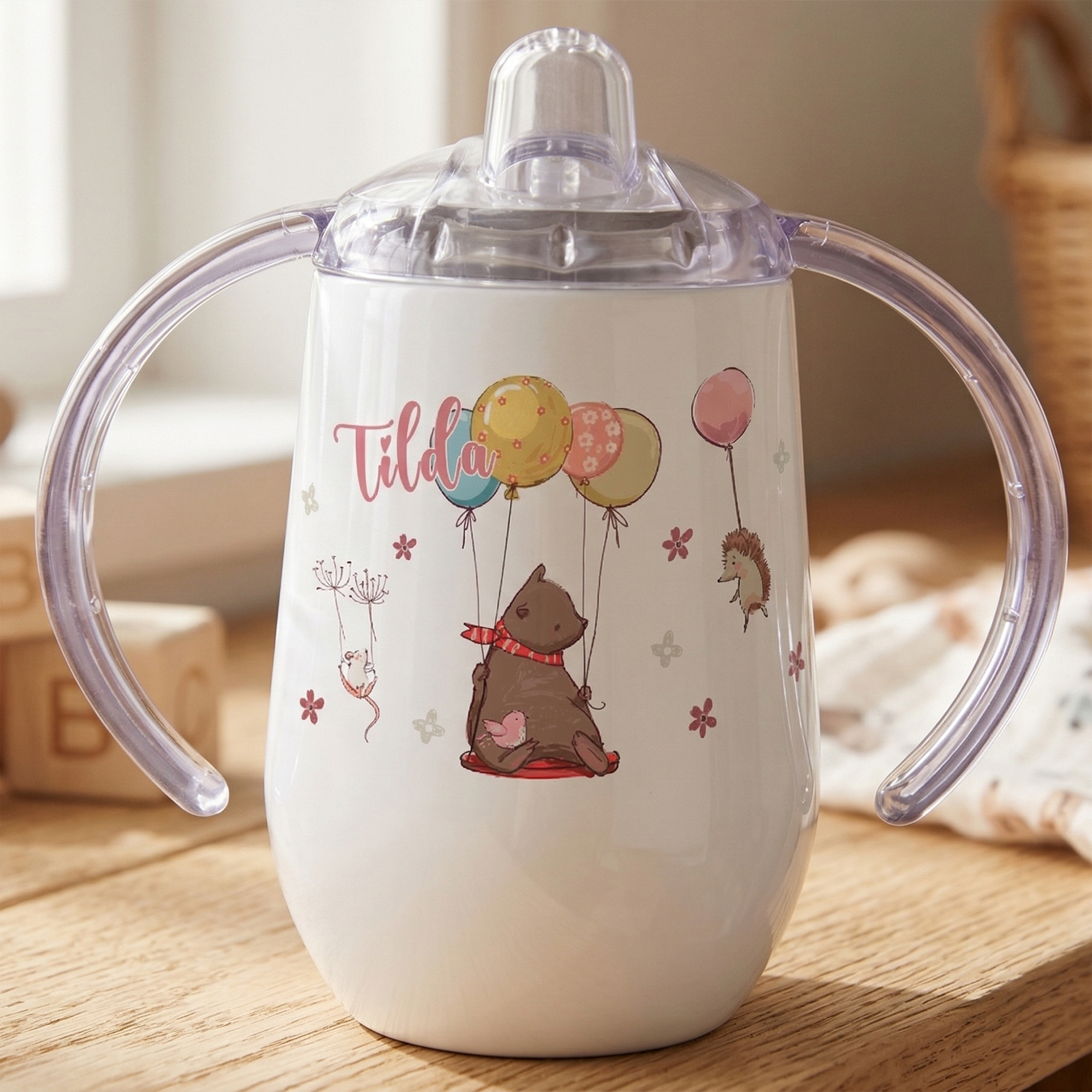 Weißer Trinkbecher mit bunten Tiermotiven und Henkel.