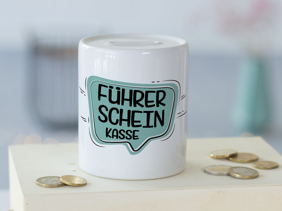 Weißes Sparschwein mit Aufschrift "Führerschein Kasse" in Türkis.