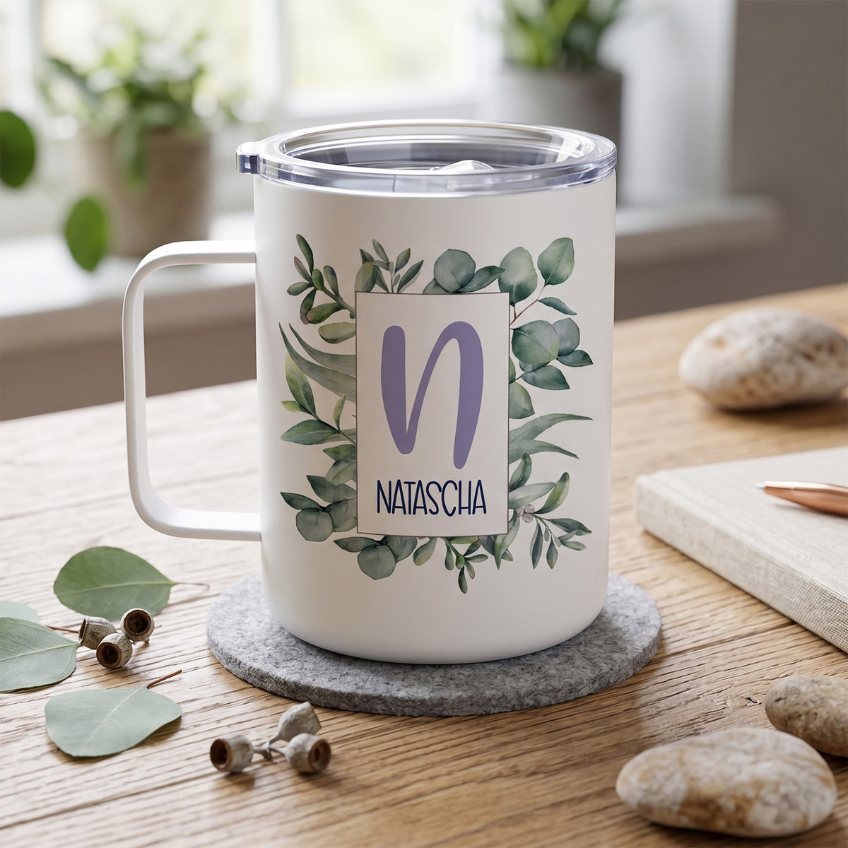Weißer Becher mit grünem Pflanzenmotiv und personalisiertem Namen.