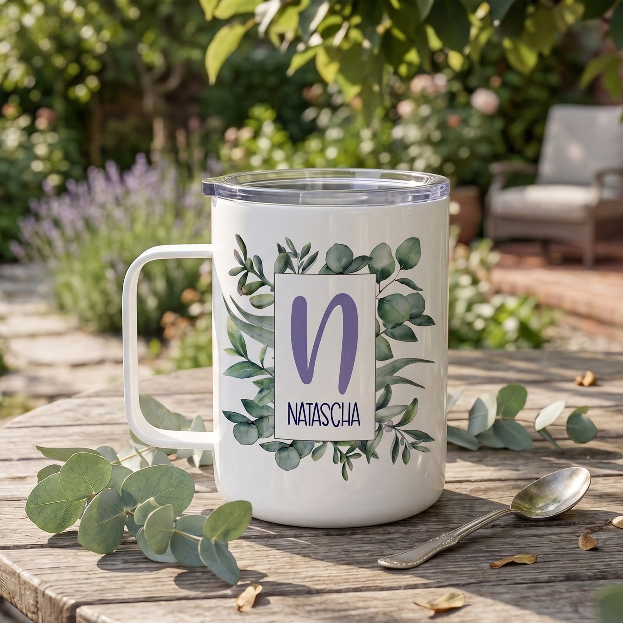 Weißer Becher mit Pflanzenmotiv und personalisiertem Namen.