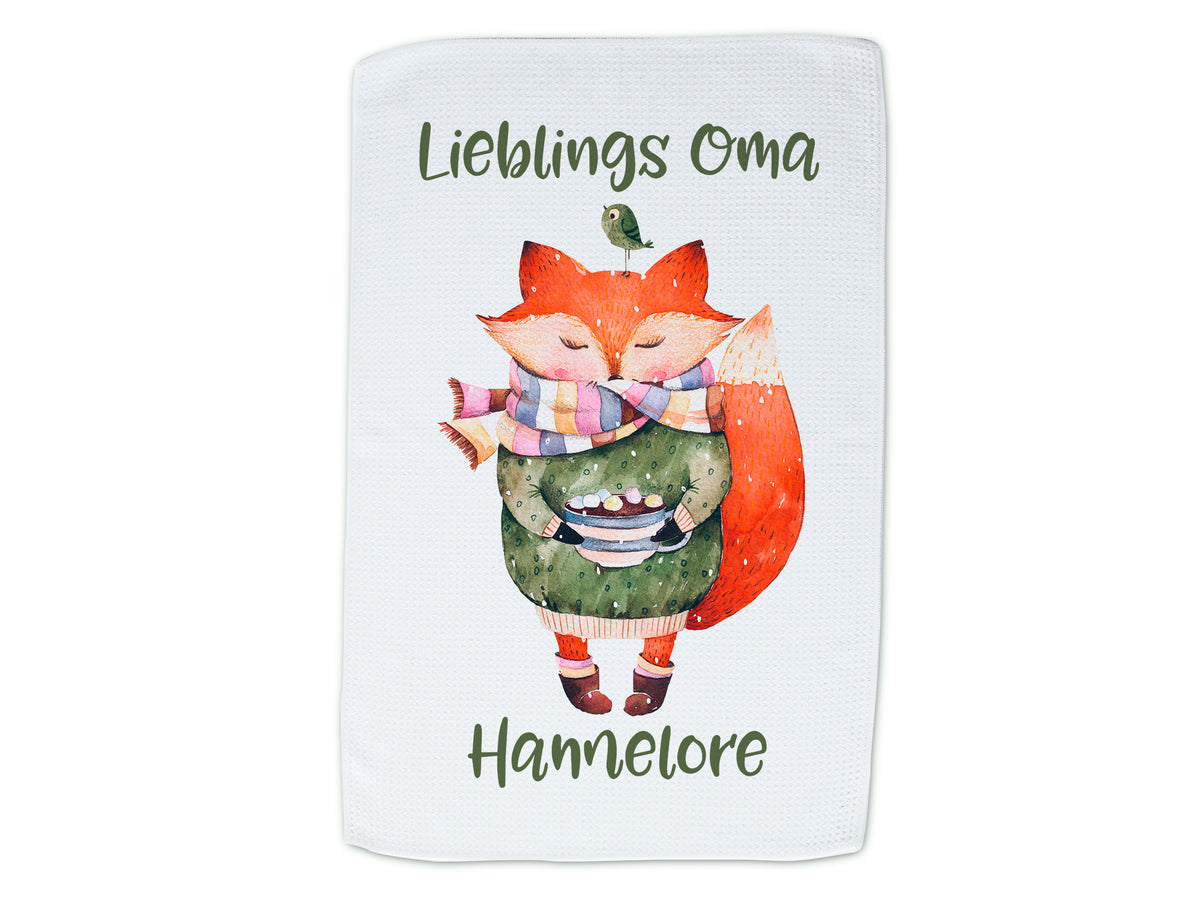 Geschirrtuch mit rotem Fuchs und grünem Kleid, beschriftet.