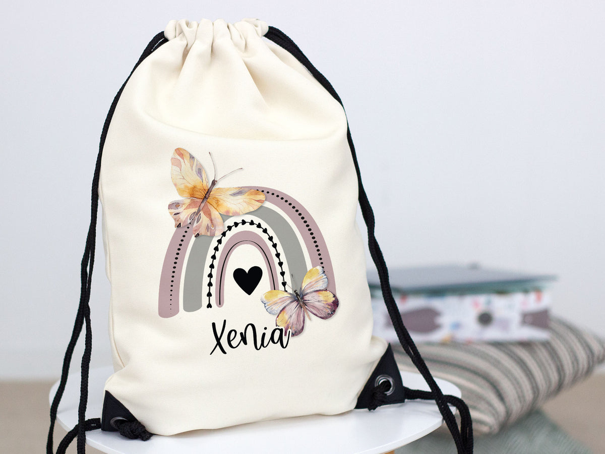 Beiger Rucksack mit Regenbogen und Schmetterlingen, personalisiert.