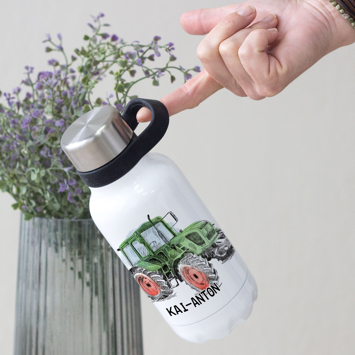 Weiße Wasserflasche mit grünem Traktor-Design und schwarzem Deckel.