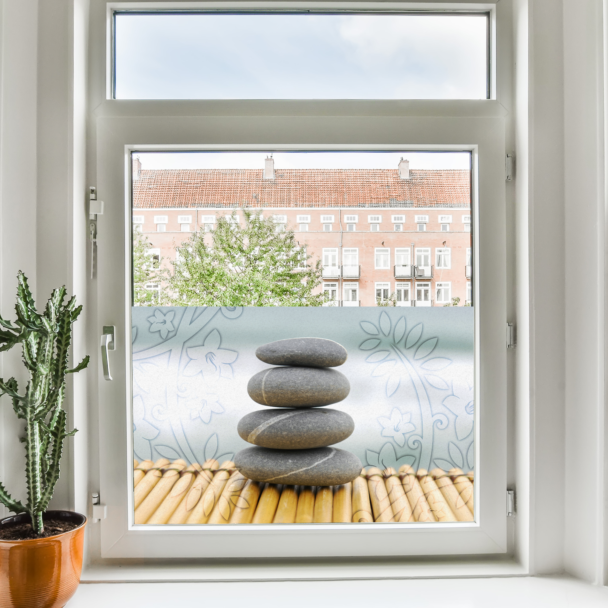 Graue Steine auf Bambus, Fenster mit Pflanzen im Hintergrund.