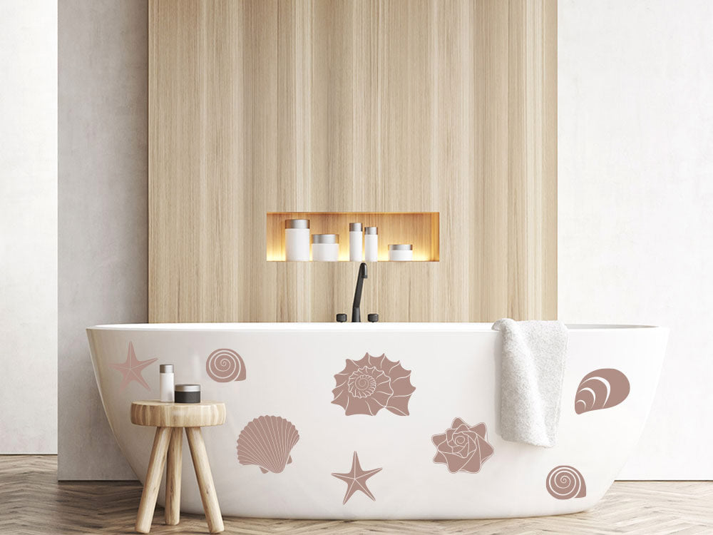 Weiße Badewanne mit rosa Muschel-Motiven und Handtuch.