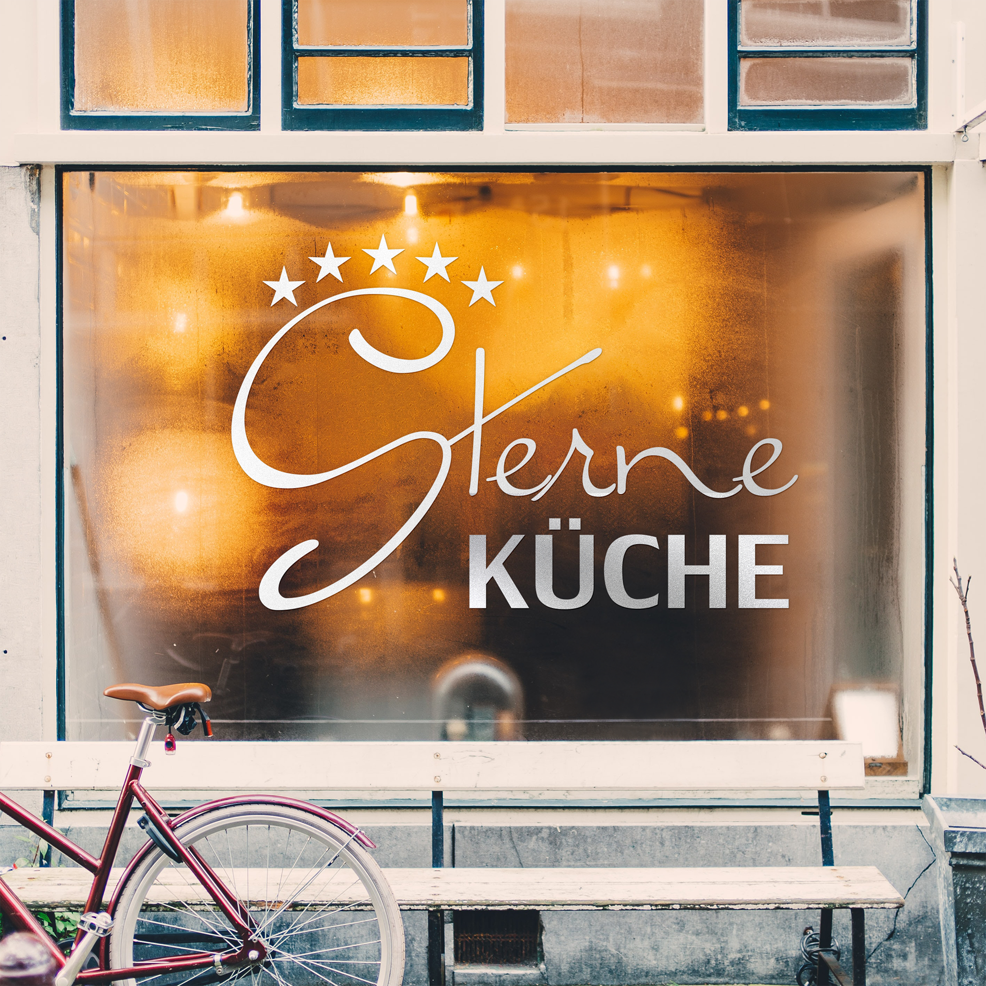 Sterne Küche, elegante Schrift, warmes Licht, Fahrrad davor.