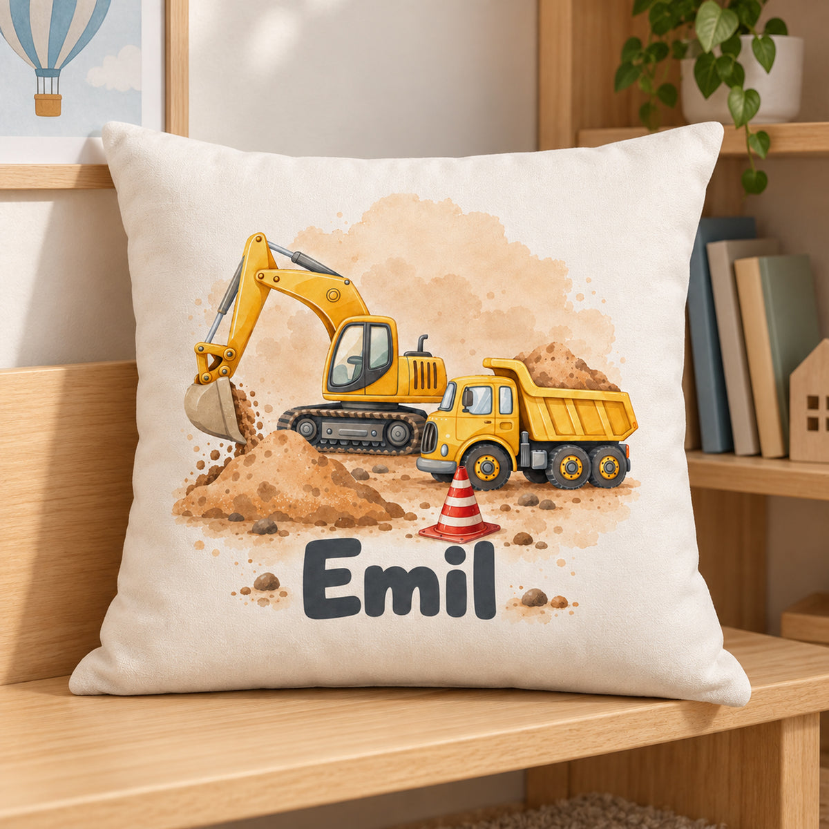 Kissenbezug mit Bagger und Kipplaster und Beispielname Emil in einer Kinderzimmer-Leseecke.