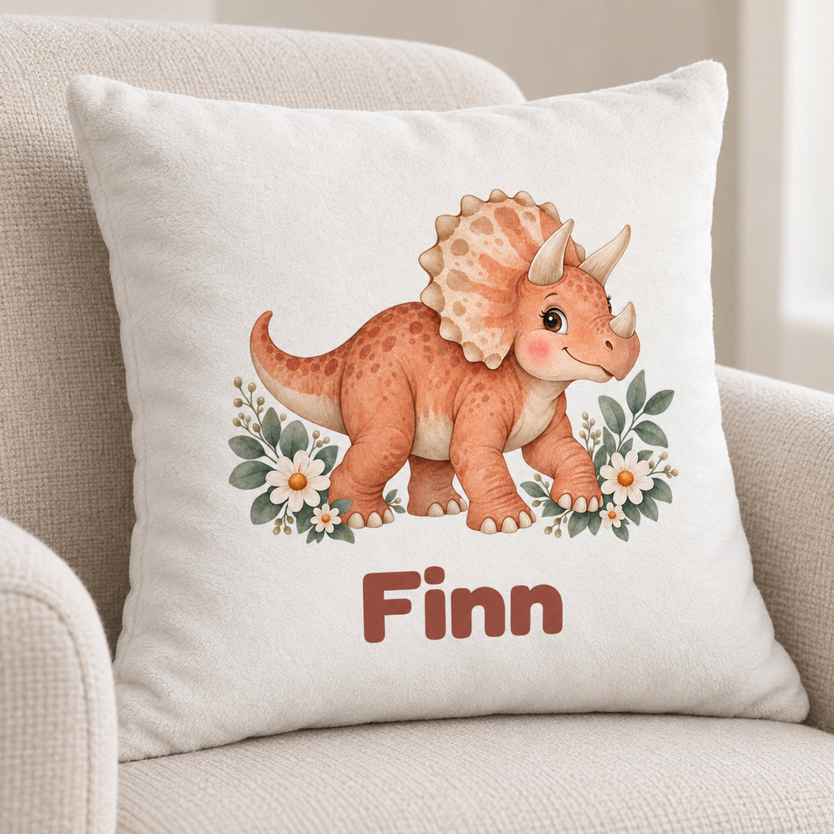 Personalisierter Dino-Kissenbezug: Triceratops mit Blumen, Beispielname Finn – Kissenbezug auf hellem Sofa
