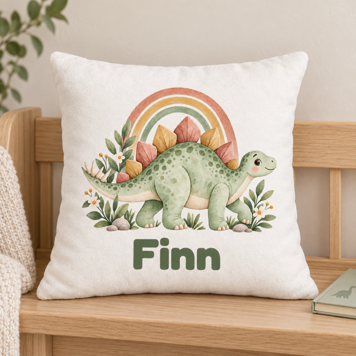 Personalisierter Dino-Kissenbezug: Stegosaurus mit Regenbogen, Beispielname Finn – Gedruckte Vorderseite auf Holzstuhl