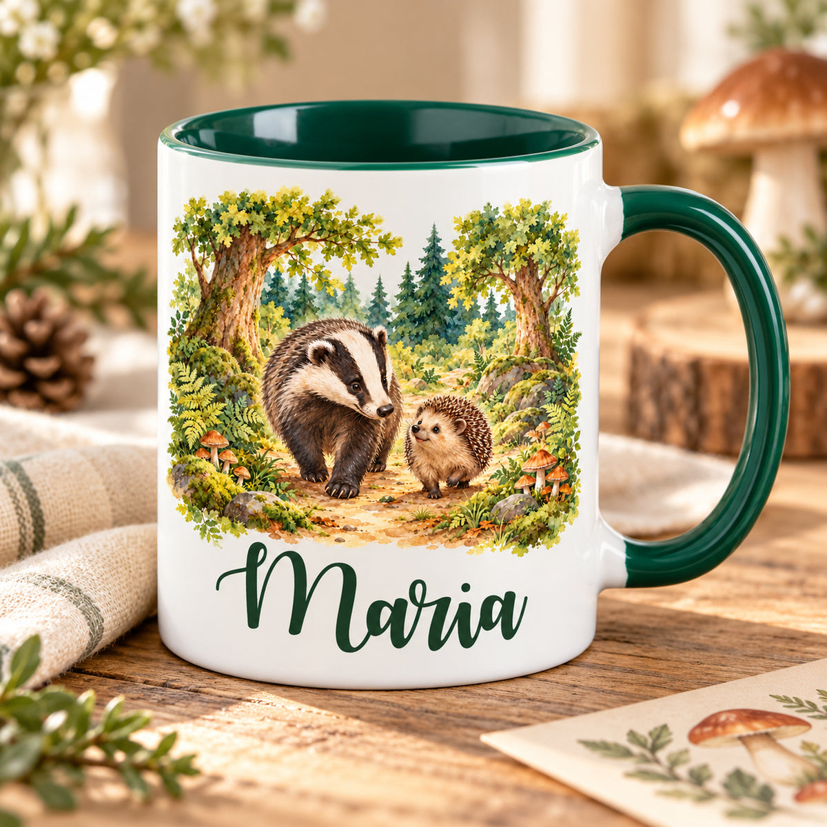 Weiße Namenstasse mit grünem Henkel und Waldmotiv: Dachs und Igel, auf einem Holztisch.