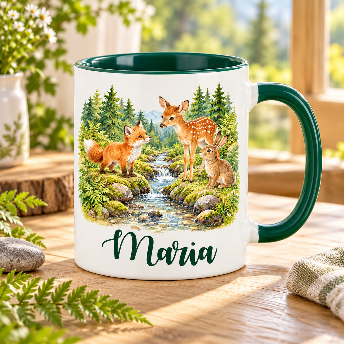 Weiße Namenstasse mit grünem Henkel und Waldmotiv: Fuchs, Rehkitz und Hase am Bach, auf einem Holztisch.