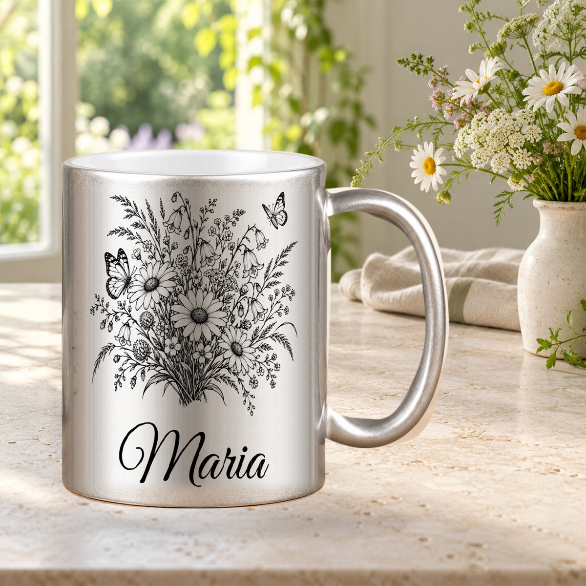 Silberne Tasse mit schwarzem Schmetterlings- und Wiesenblumenmotiv und Wunschnamen in einer dekorierten Blumenszene.
