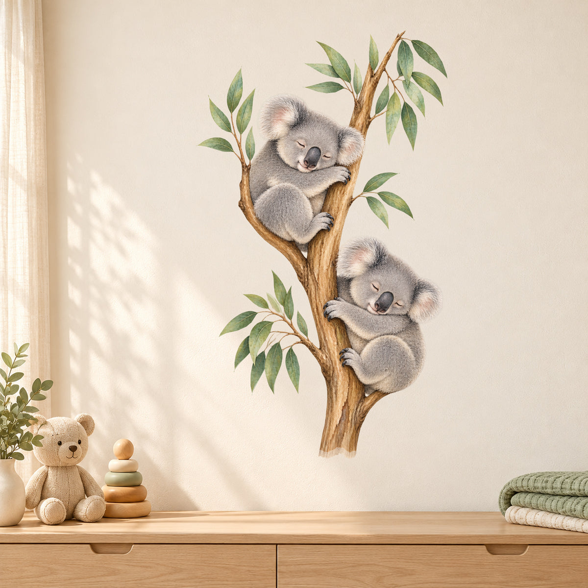 Koala-Wandtattoo Schlafenszeit an einer hellen Wand über einer Holzbank mit Koala-Stofftier, Stapelspielzeug und grüner Decke.