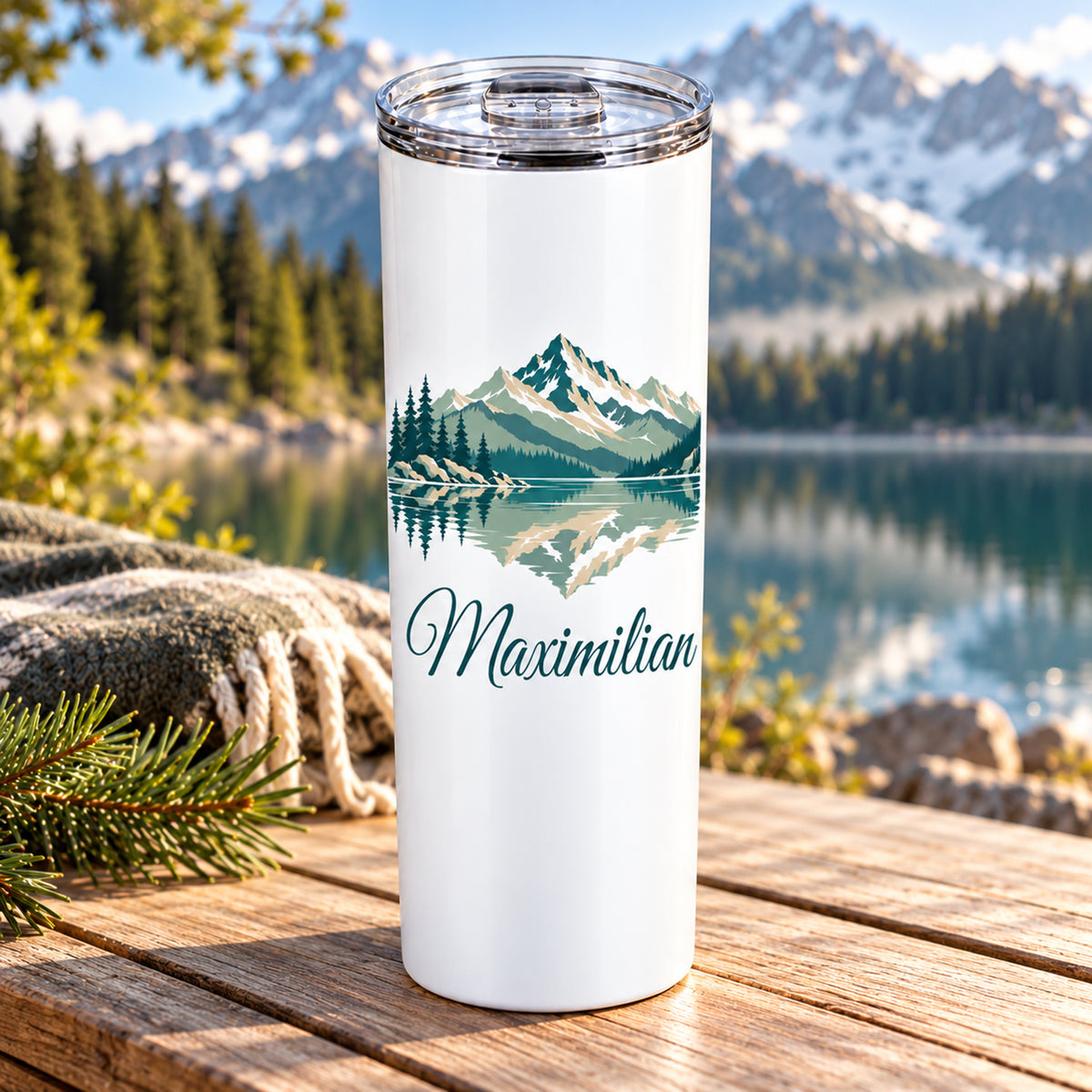 Thermobecher mit Bergsee und Tannen und Wunschname, seitlich auf einem Tisch dargestellt.
