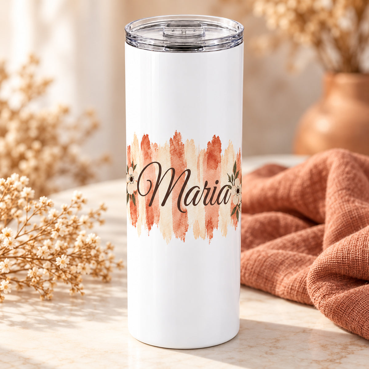 Weißer Thermobecher mit Motiv Terrakottablüte, personalisiertem Namen auf einem dekorierten Geschenktisch.