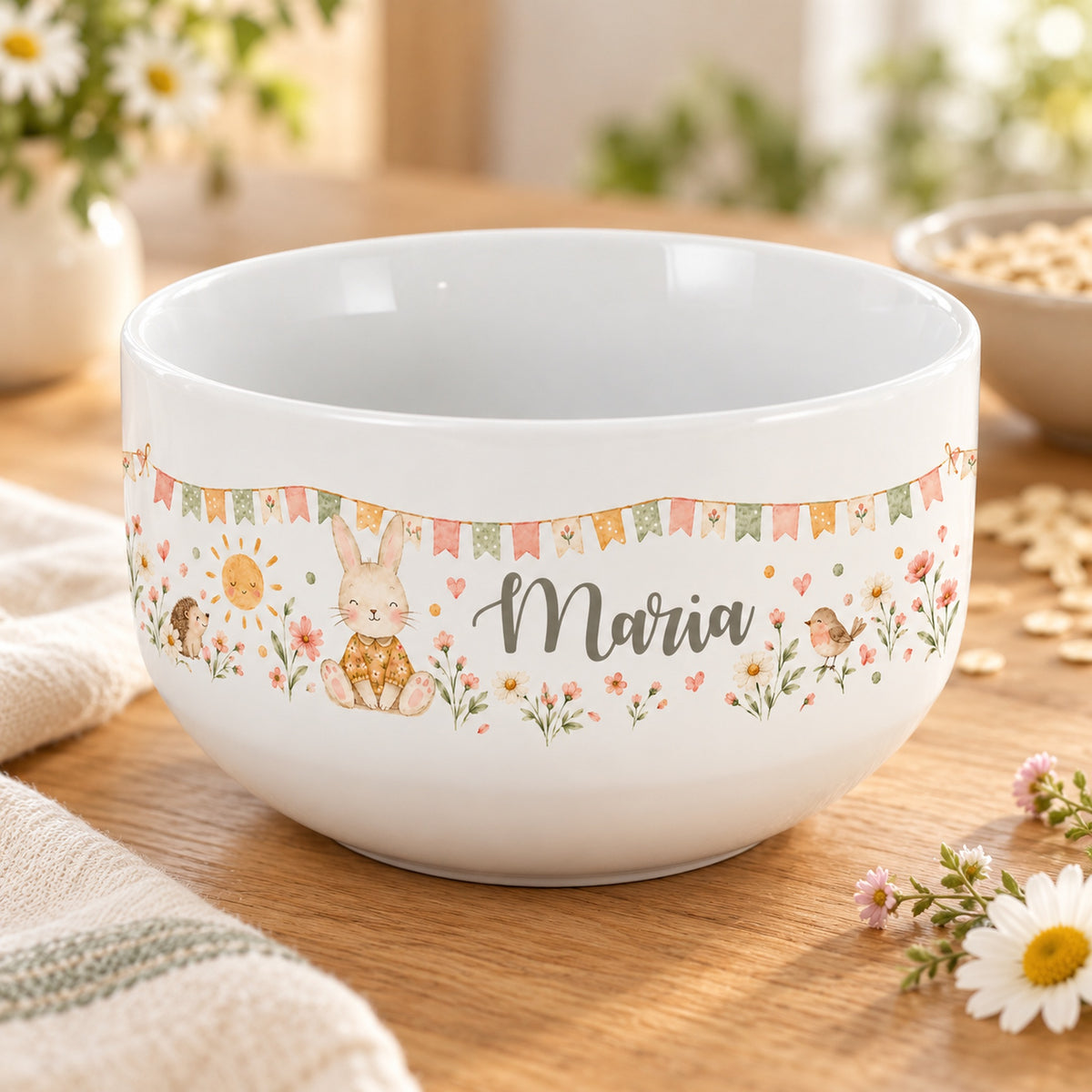 Personalisierte Keramik-Müslischale mit Häschen, Sonne, Igel und Vogel und Blumen auf einem hellen Tisch.