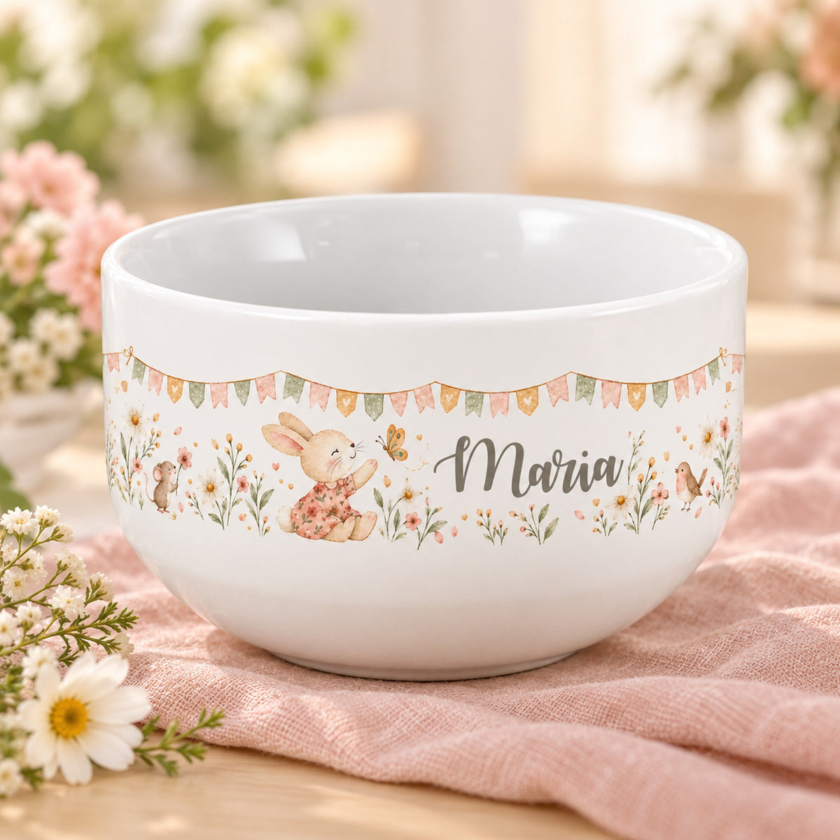 Personalisierte Keramik-Müslischale mit Häschen, Schmetterling, Maus und Vogel und Blumen auf einem hellen Tisch.
