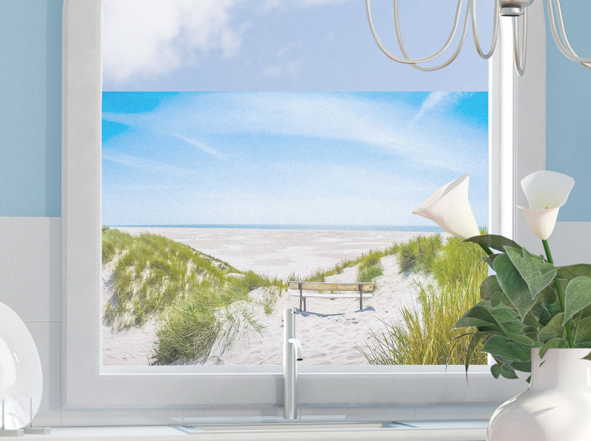Blick auf Strand mit Sanddünen und blauem Himmel.