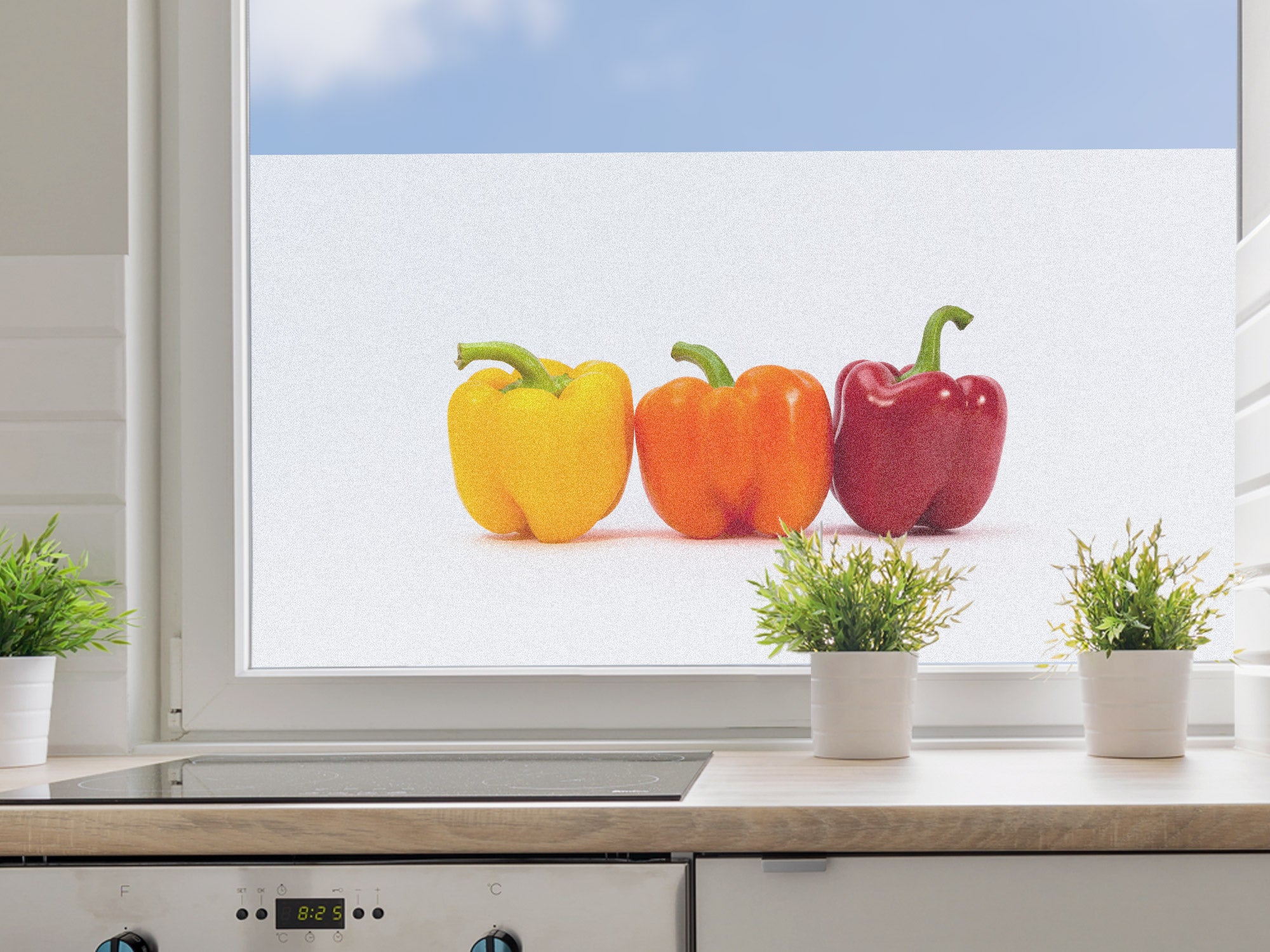Drei Paprika in Gelb, Orange und Rot am Fenster.