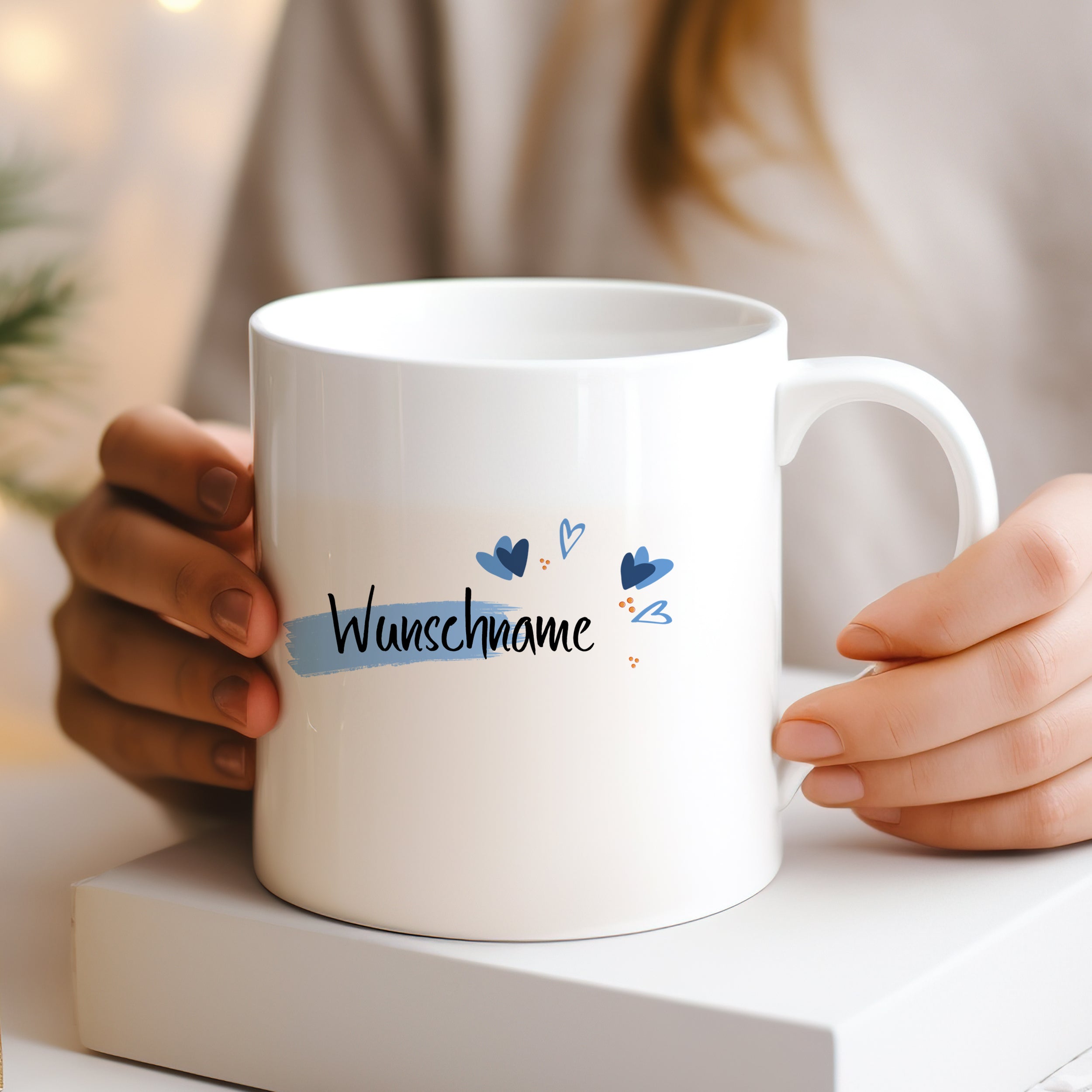 Weiße Tasse mit personalisiertem Wunschname und blauen Herzen.