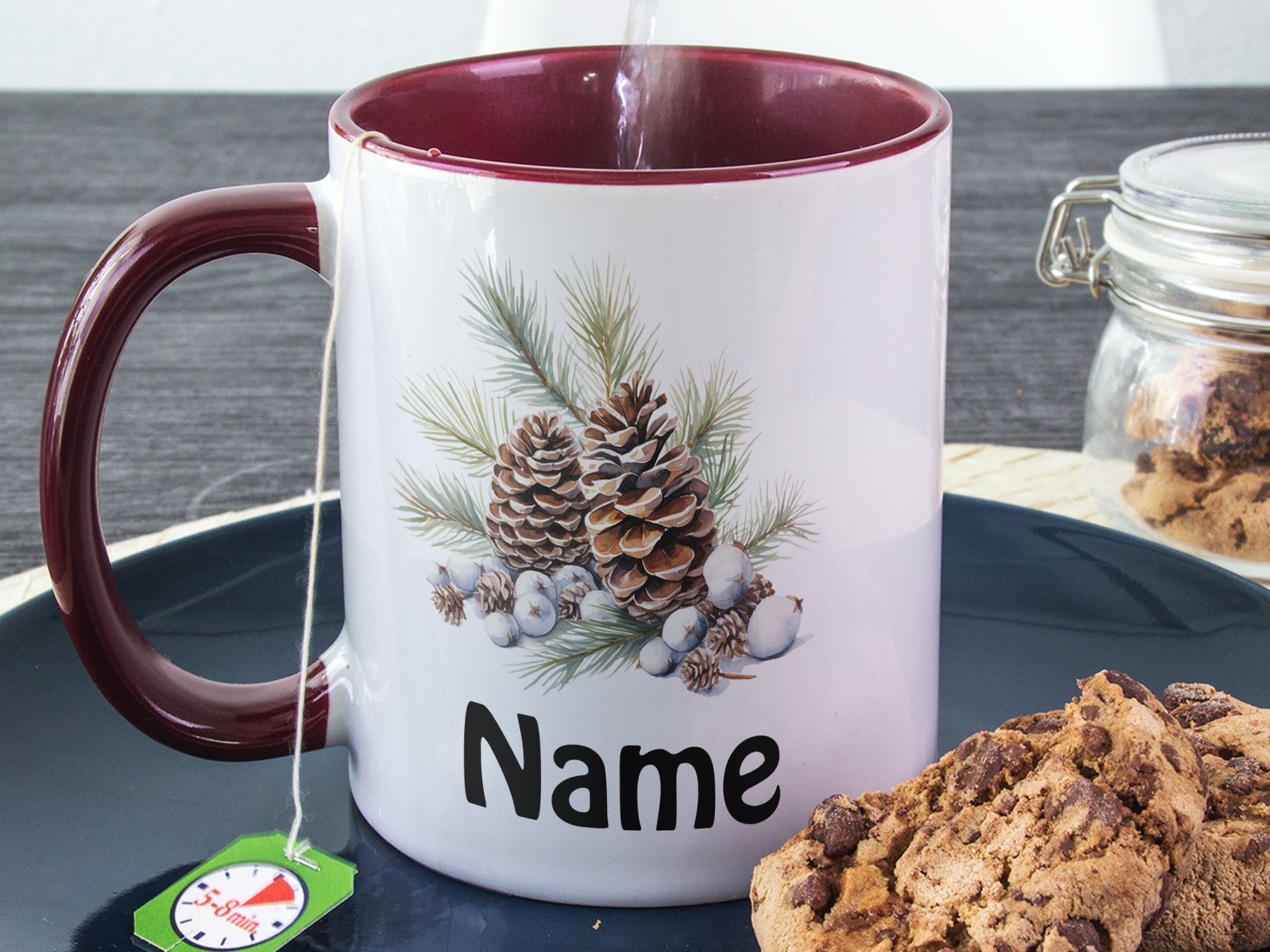 Kaffeetasse mit maroonfarbenem Henkel und Weihnachtsmotiv.