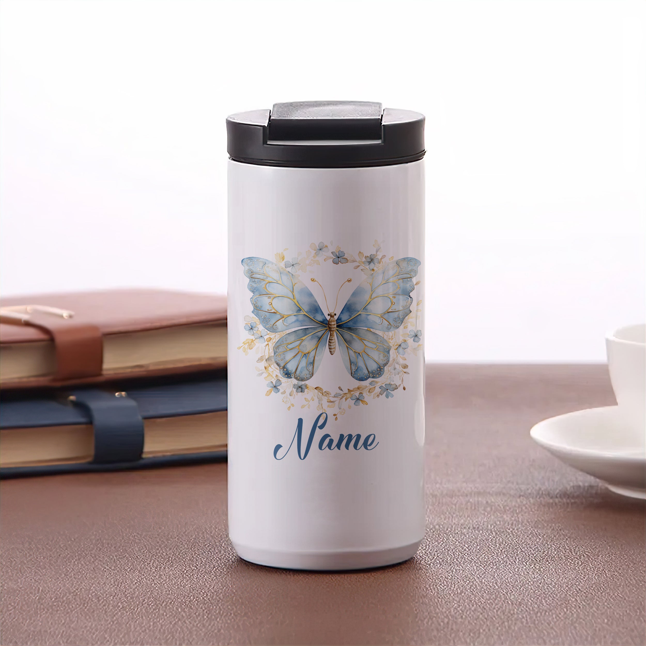 Weißer Kaffeebecher mit blauen Schmetterlingen und personalisierbarem Namen.