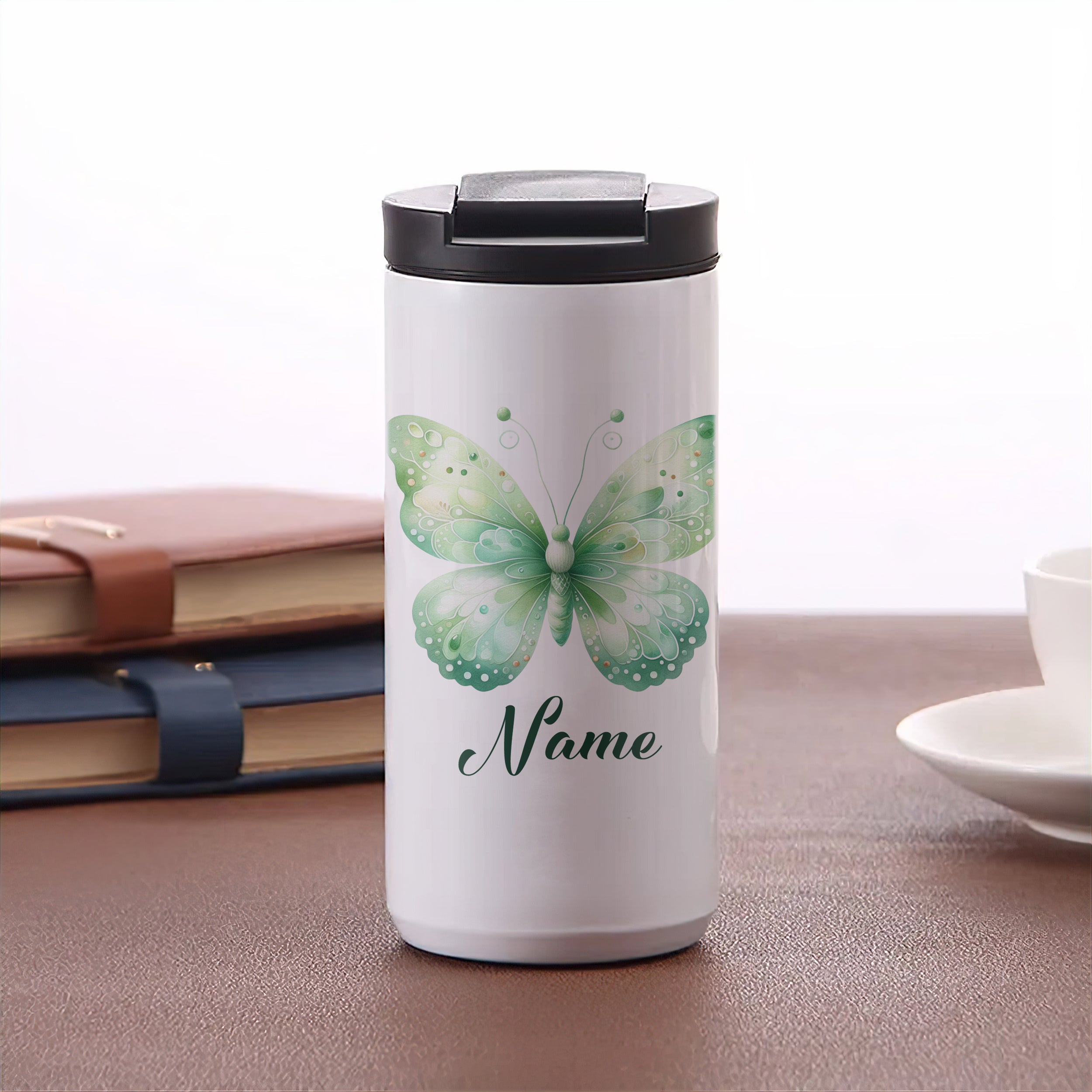 Weißer Becher mit grünem Schmetterlingsdesign und Name.