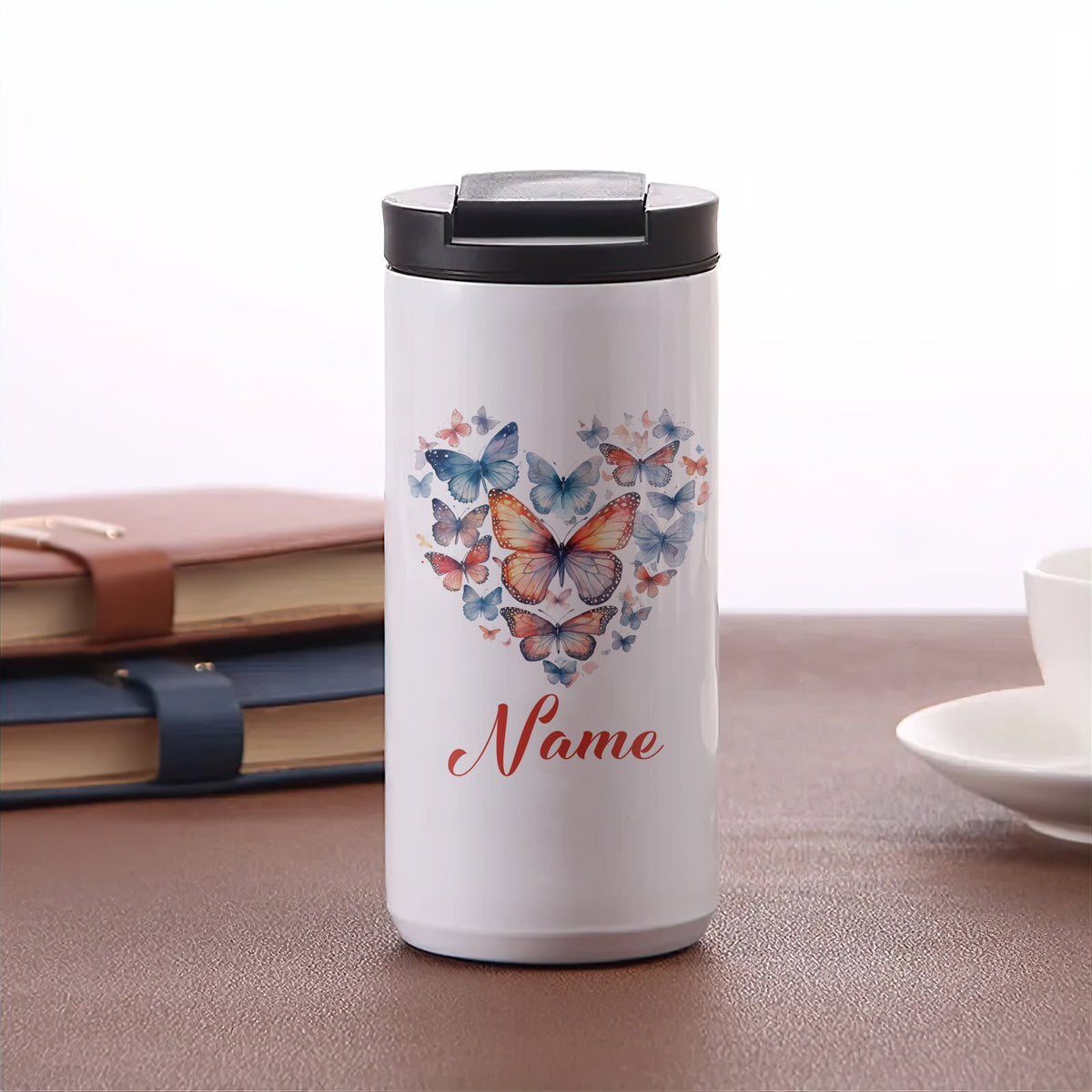 Weißer Thermobecher mit bunten Schmetterlingen und personalisierbarem Namen.