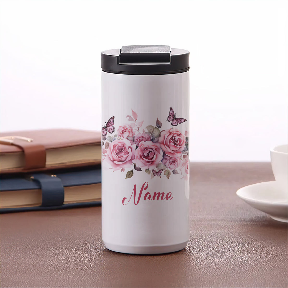 Weißer Thermobecher mit rosa Blumen und Schmetterlingen.