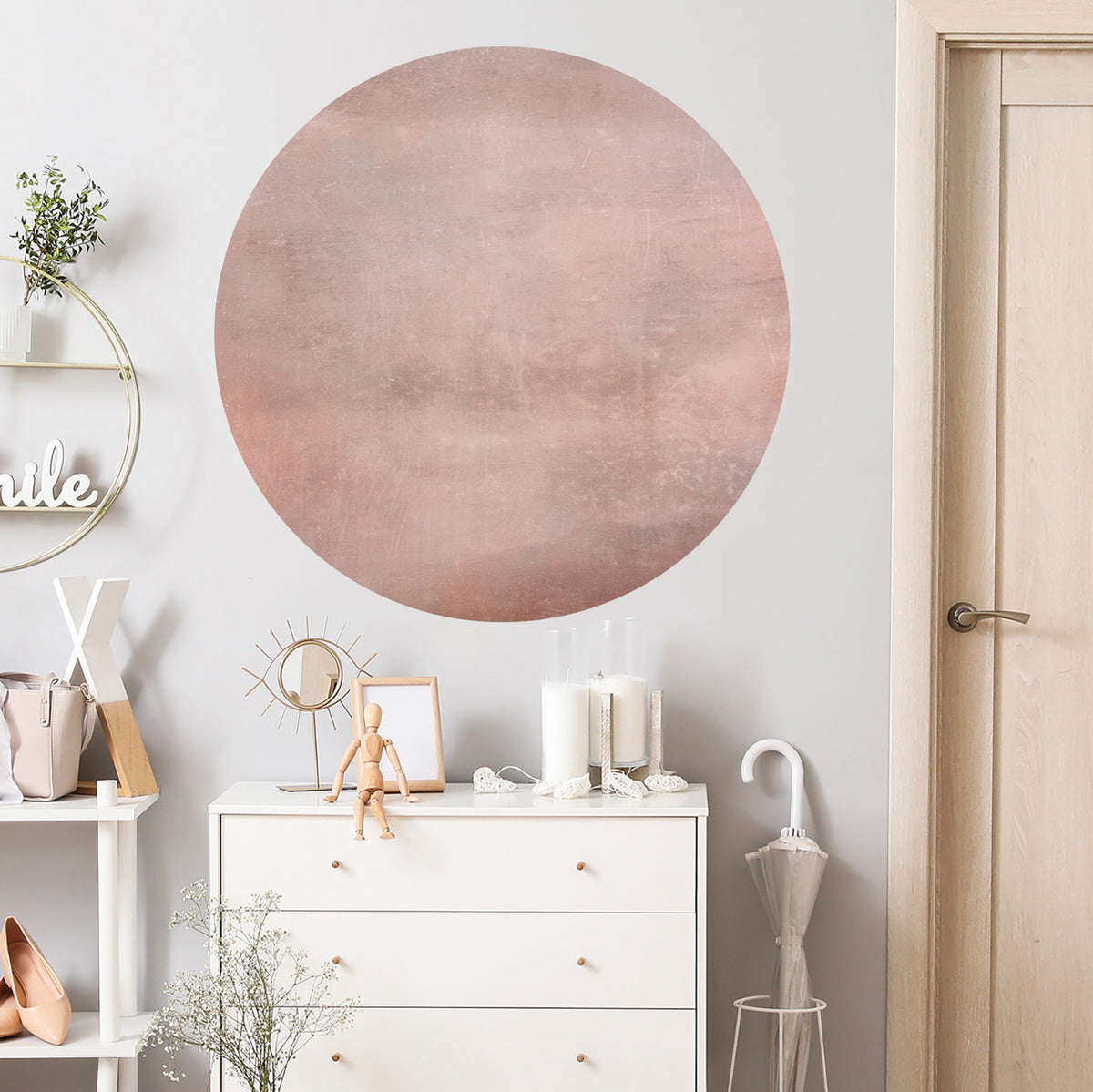 Runder, roségoldener Wandaufkleber auf hellgrauer Wand.