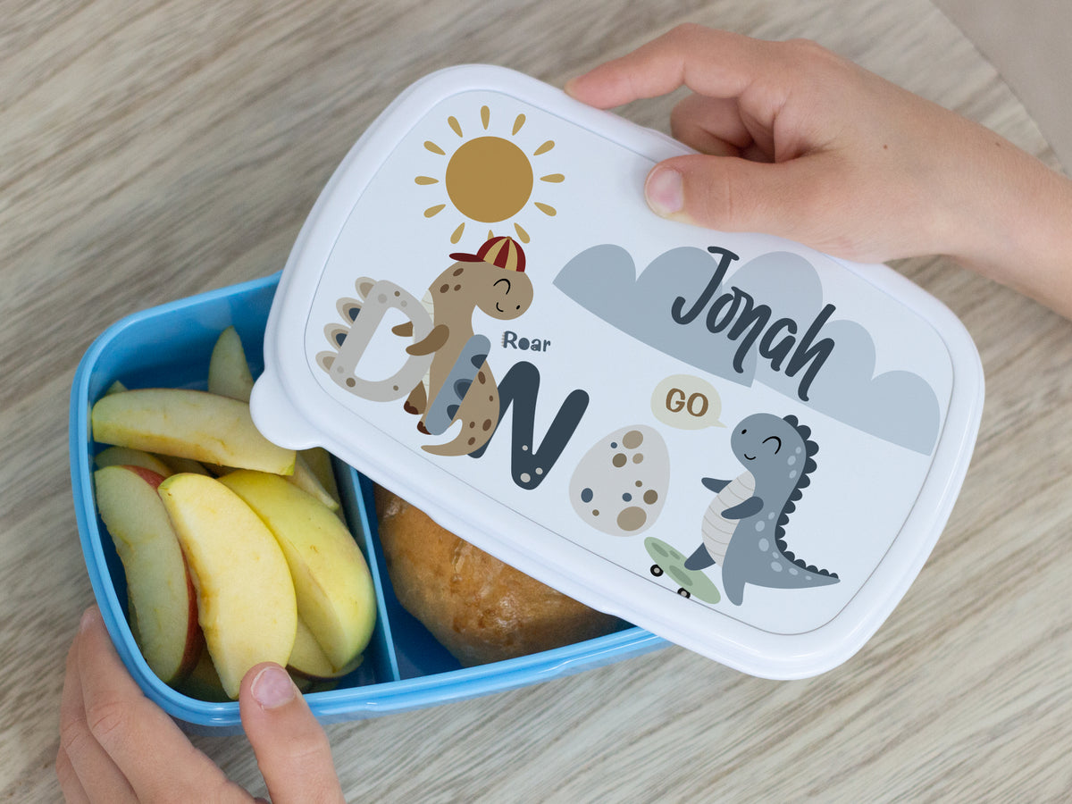 Bento-Box in Blau mit Dinosaurier-Motiv und Äpfeln.