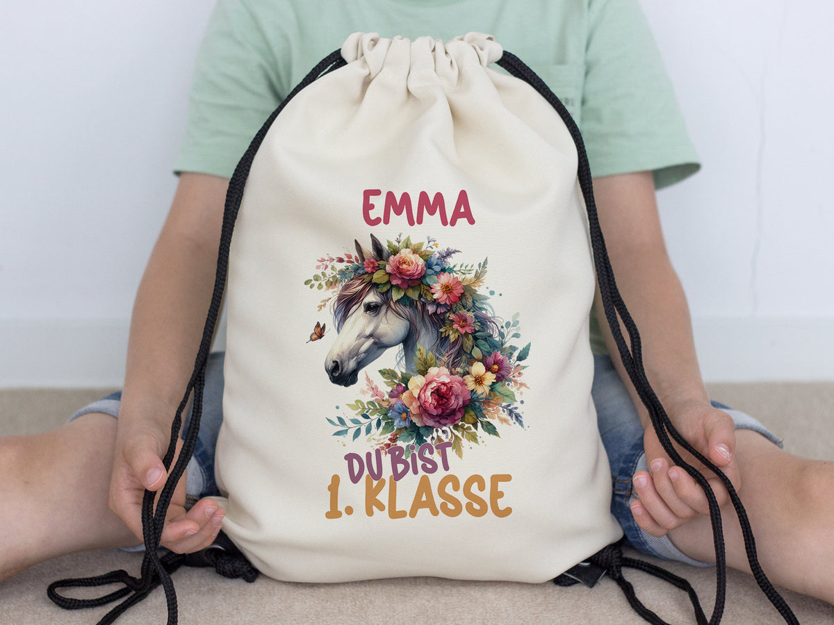 Beige Turnbeutel mit Einhorn-Motiv und bunten Blumen.