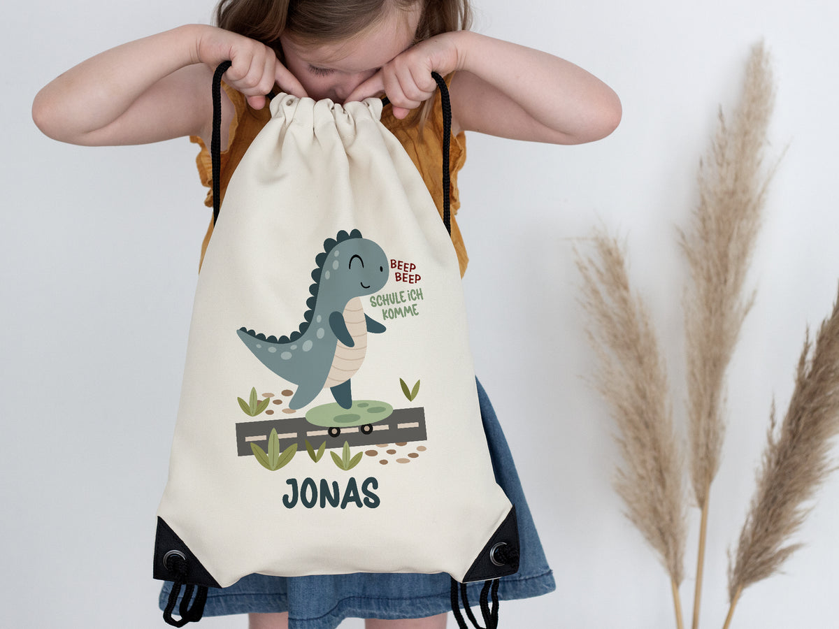 Beiger Rucksack mit Dinosaurier-Motiv und Namen Jonas.