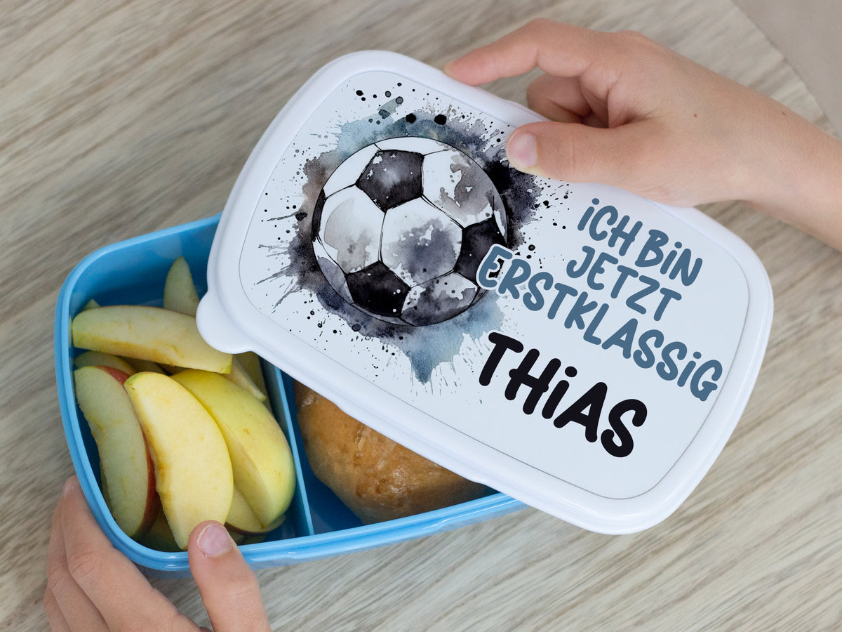 Blaue Brotdose mit Fußballmotiv und Äpfeln.