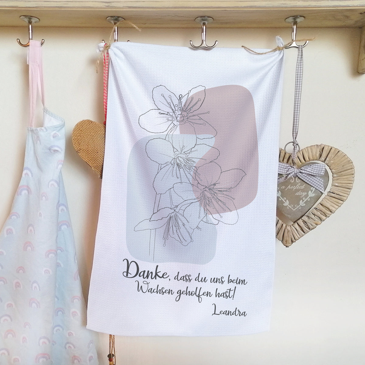 Geschirrtuch mit Blumenmotiv und Dankestext in Pastellfarben.