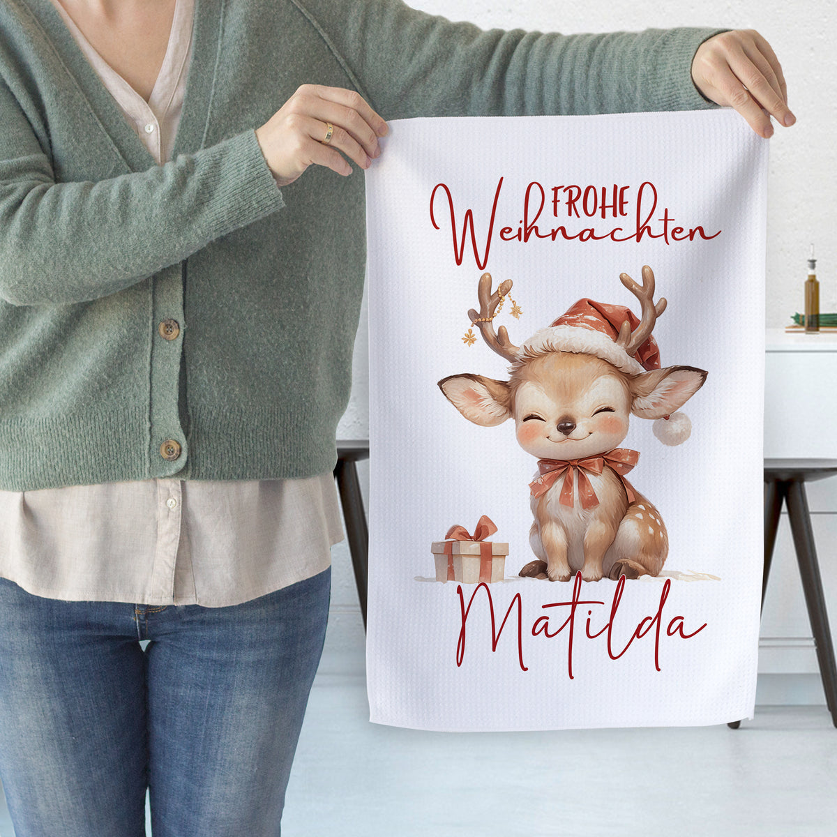 Weihnachtliches Handtuch mit niedlichem Rentier und rotem Text.