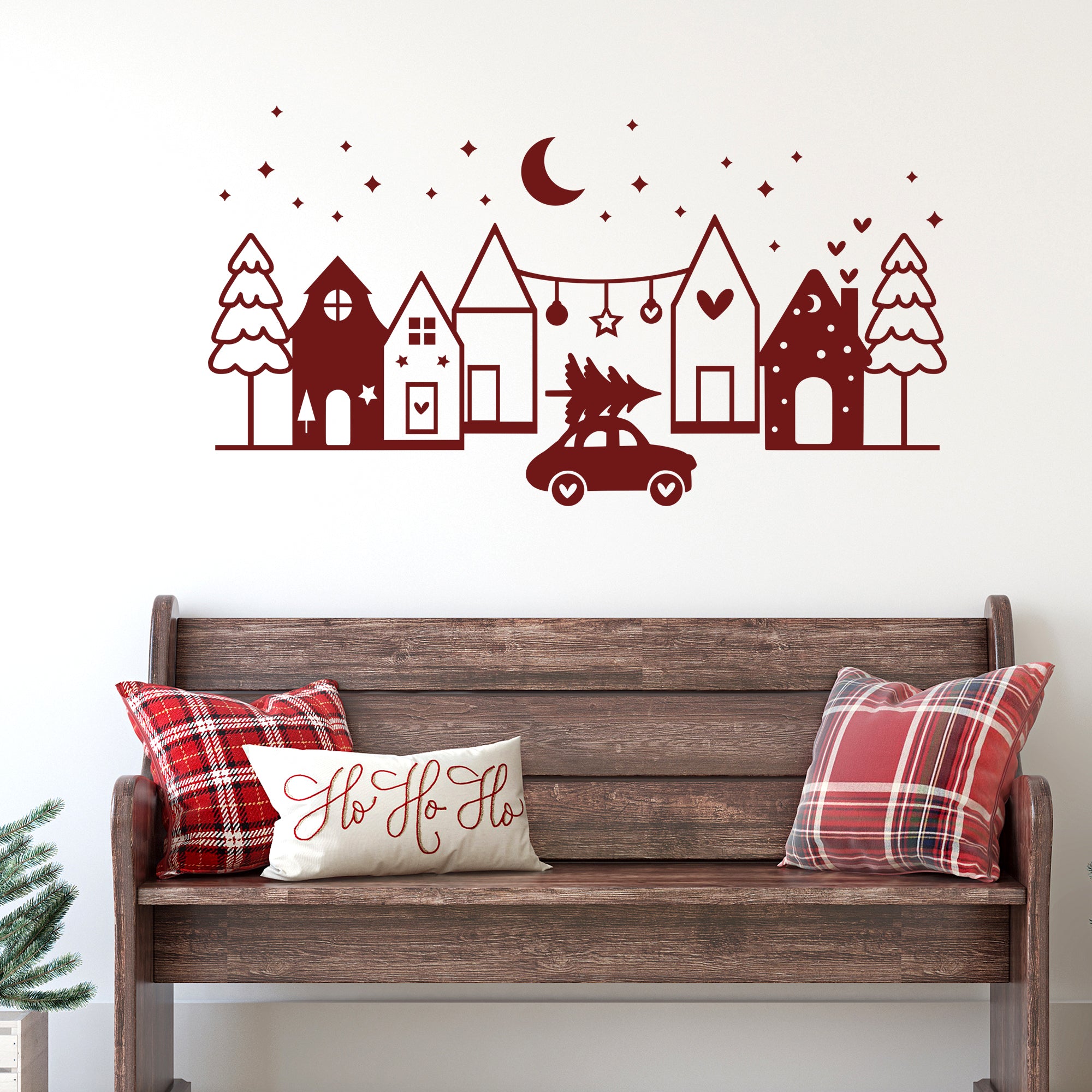 Rote Wanddekoration mit Häusern, Auto und Weihnachtsbaum.