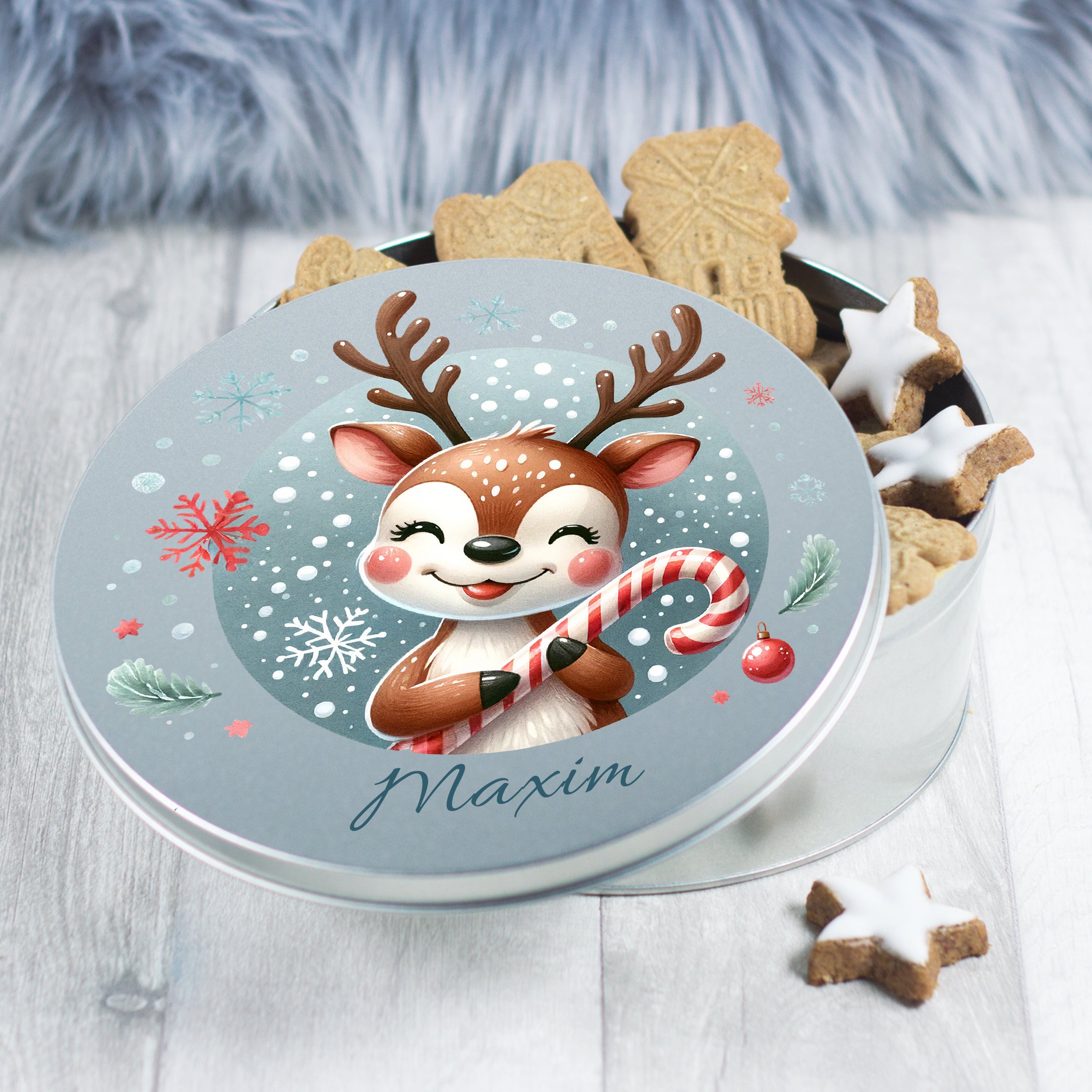 Runde Blechdose mit Rentier-Motiv und Weihnachtsplätzchen.