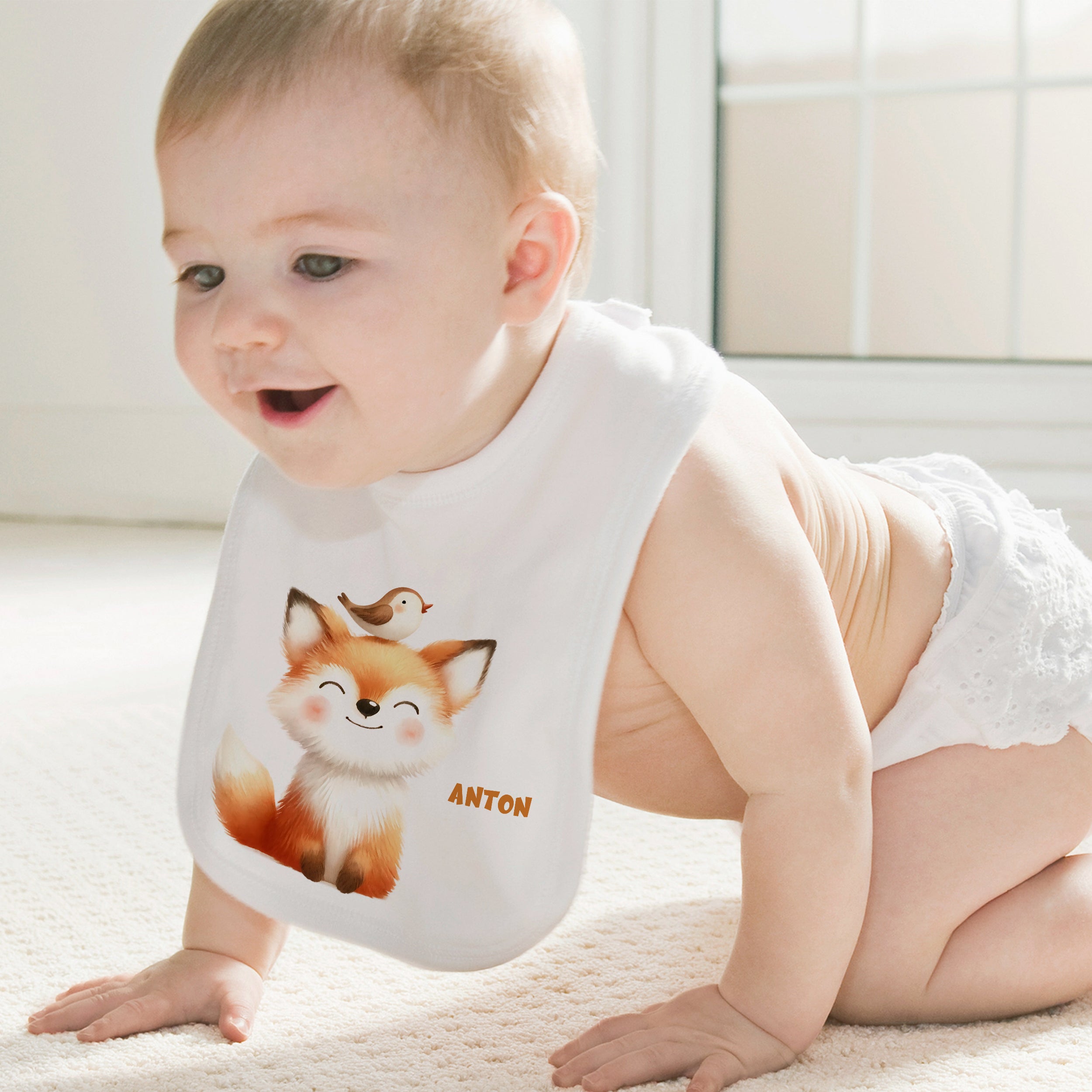 Baby mit weißem Lätzchen und Fuchs-Motiv.