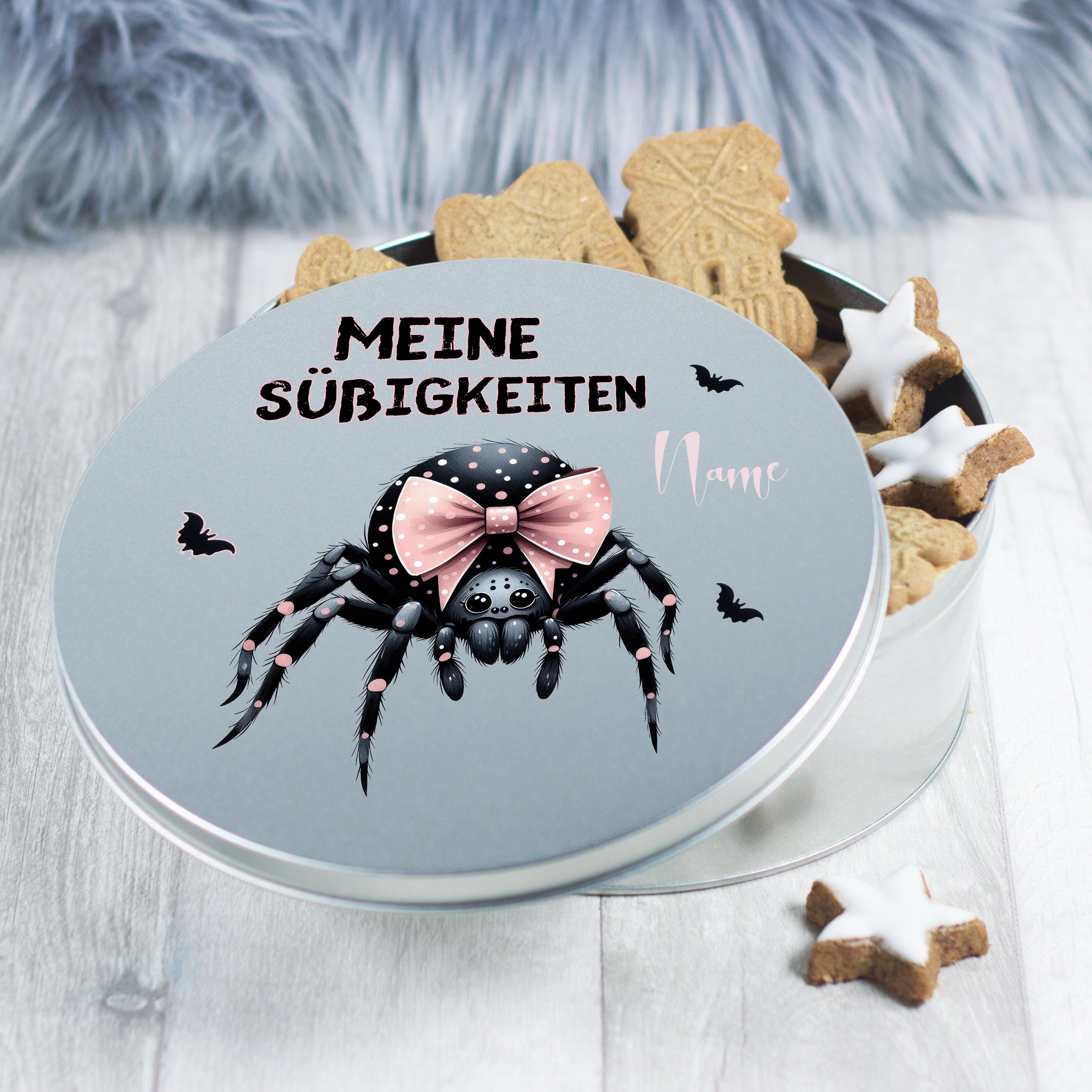 Runde Dose mit schwarzer Spinne und pinkem Schleifenmotiv.