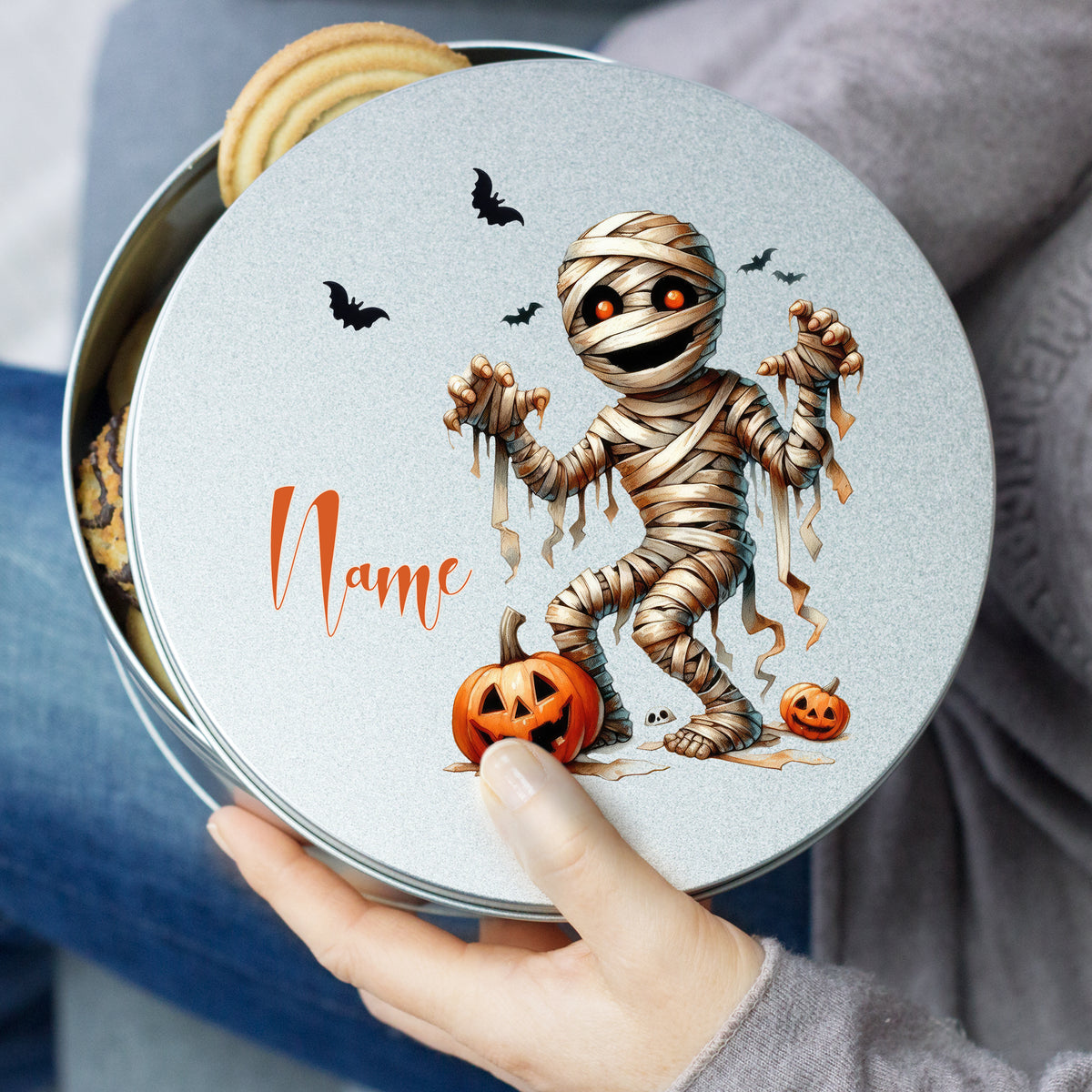 Mumienmotiv auf grauem Keksdose mit Kürbis und Fledermäusen.