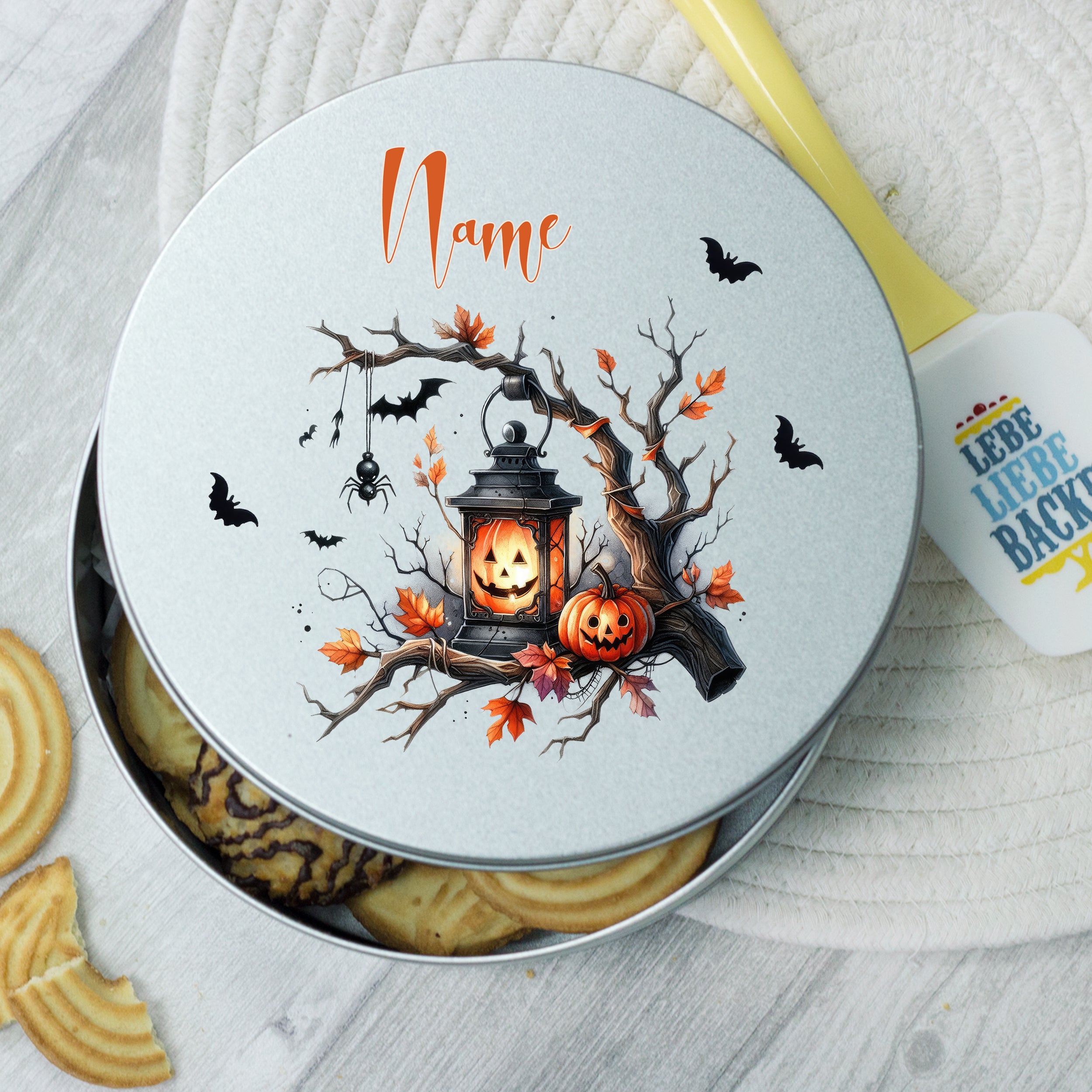 Graue Keksdose mit Halloween-Motiv, Laterne und Kürbissen.