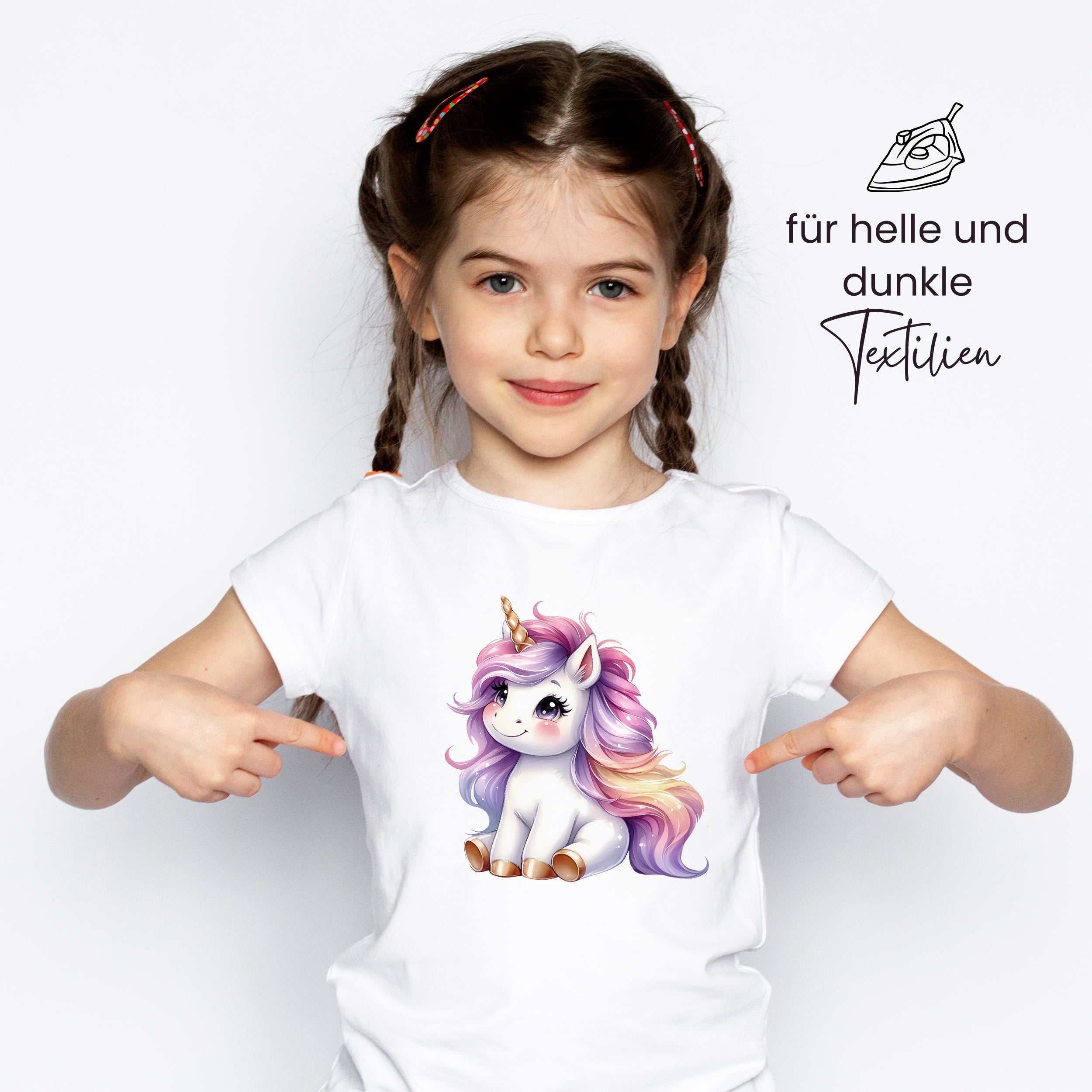 Weißes T-Shirt mit buntem Einhorn-Motiv, Mädchen zeigt darauf.