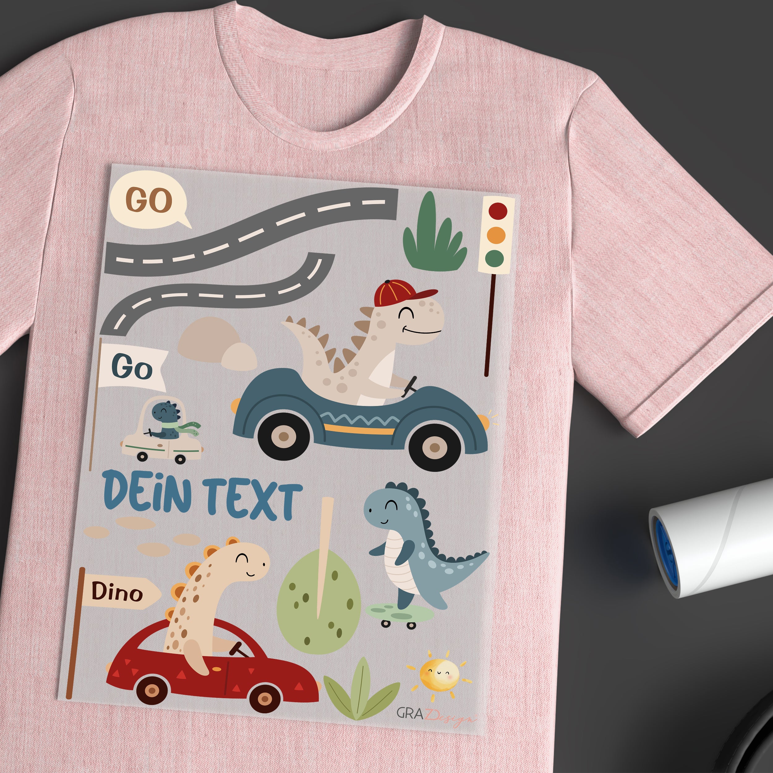 Rosa T-Shirt mit Dinosauriern und bunten Fahrzeugen.