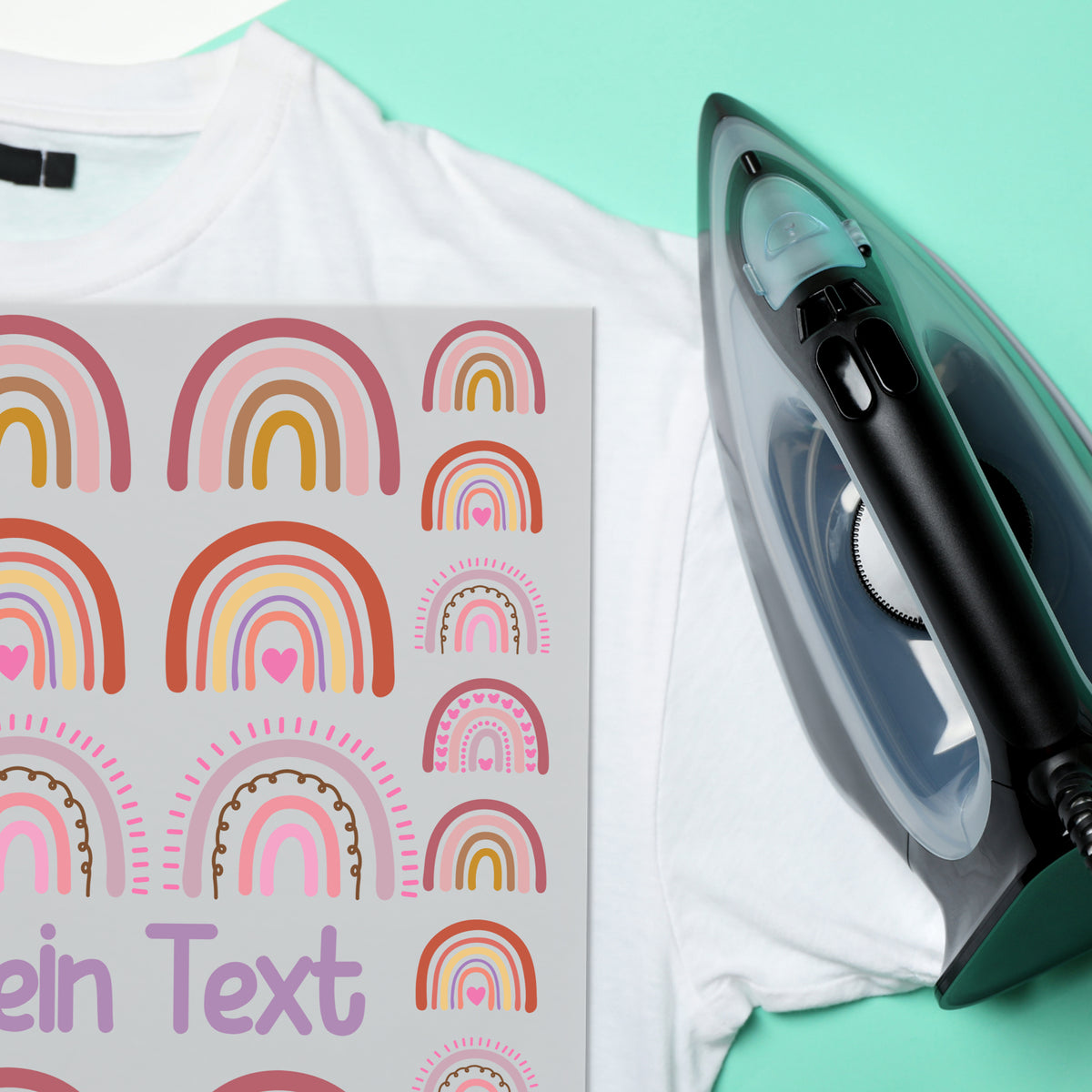 Bügeleisen neben weißem T-Shirt mit bunten Regenbogen-Motiven.