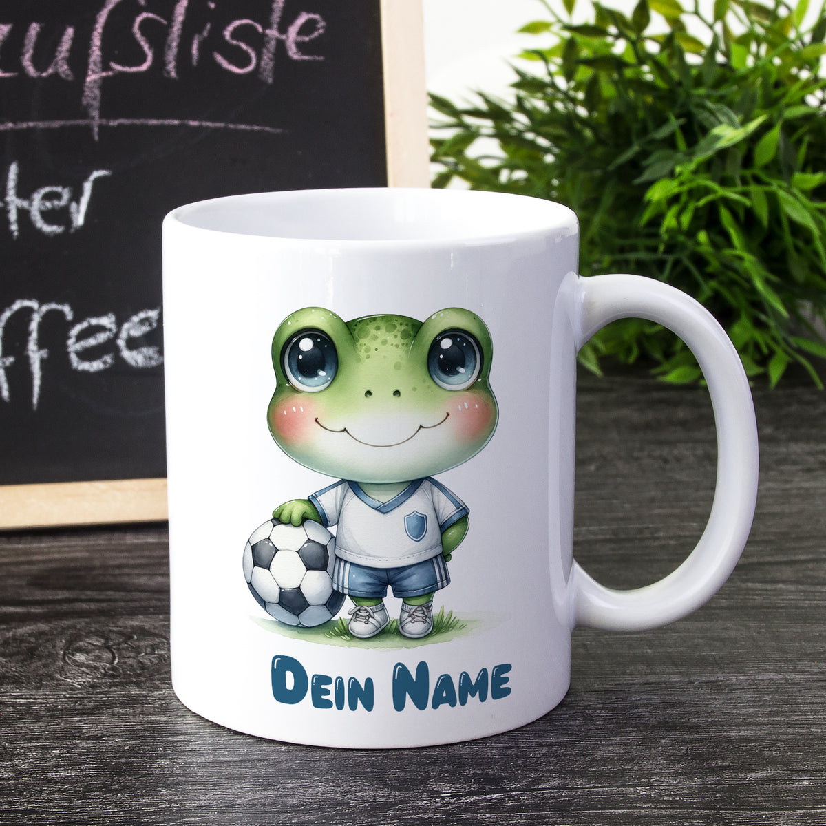 Weißer Becher mit Frosch-Motiv und Fußball.