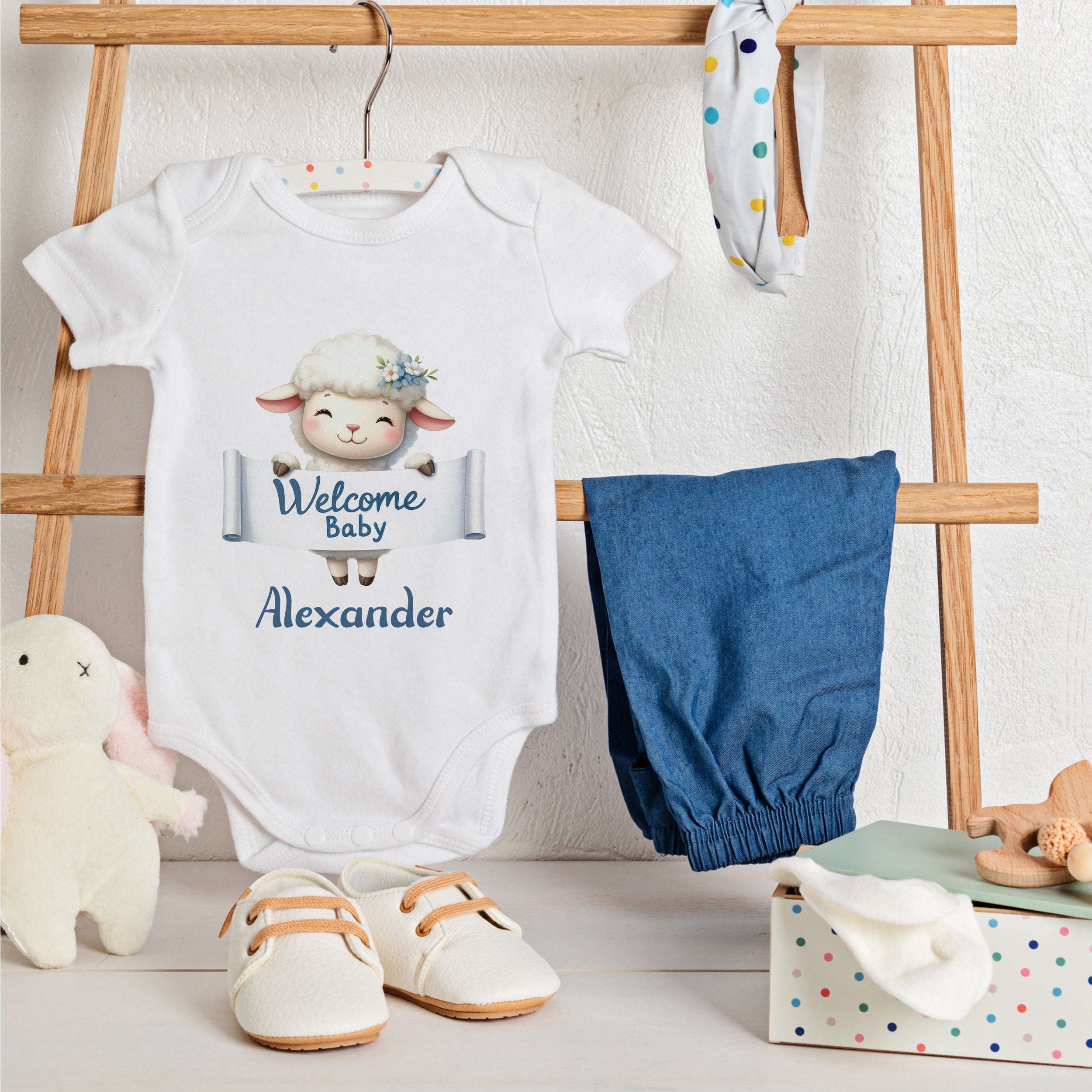 Weißes Babybody mit Schaf-Motiv, blauem Hosen und Schuhen.