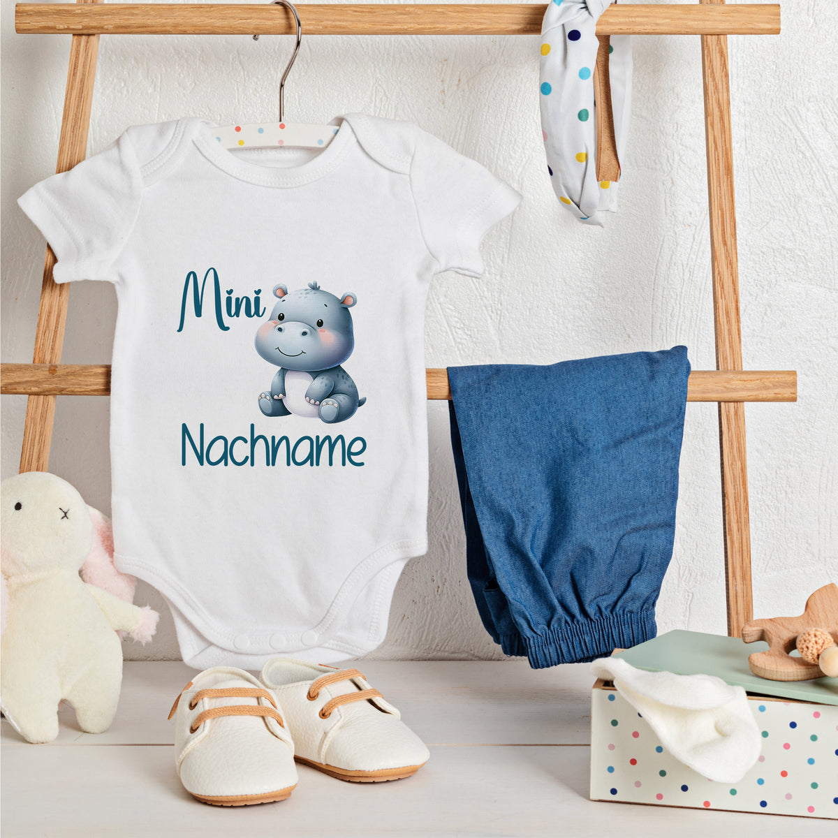 Weißes Babybody mit Nilpferd-Motiv und blauem Text.
