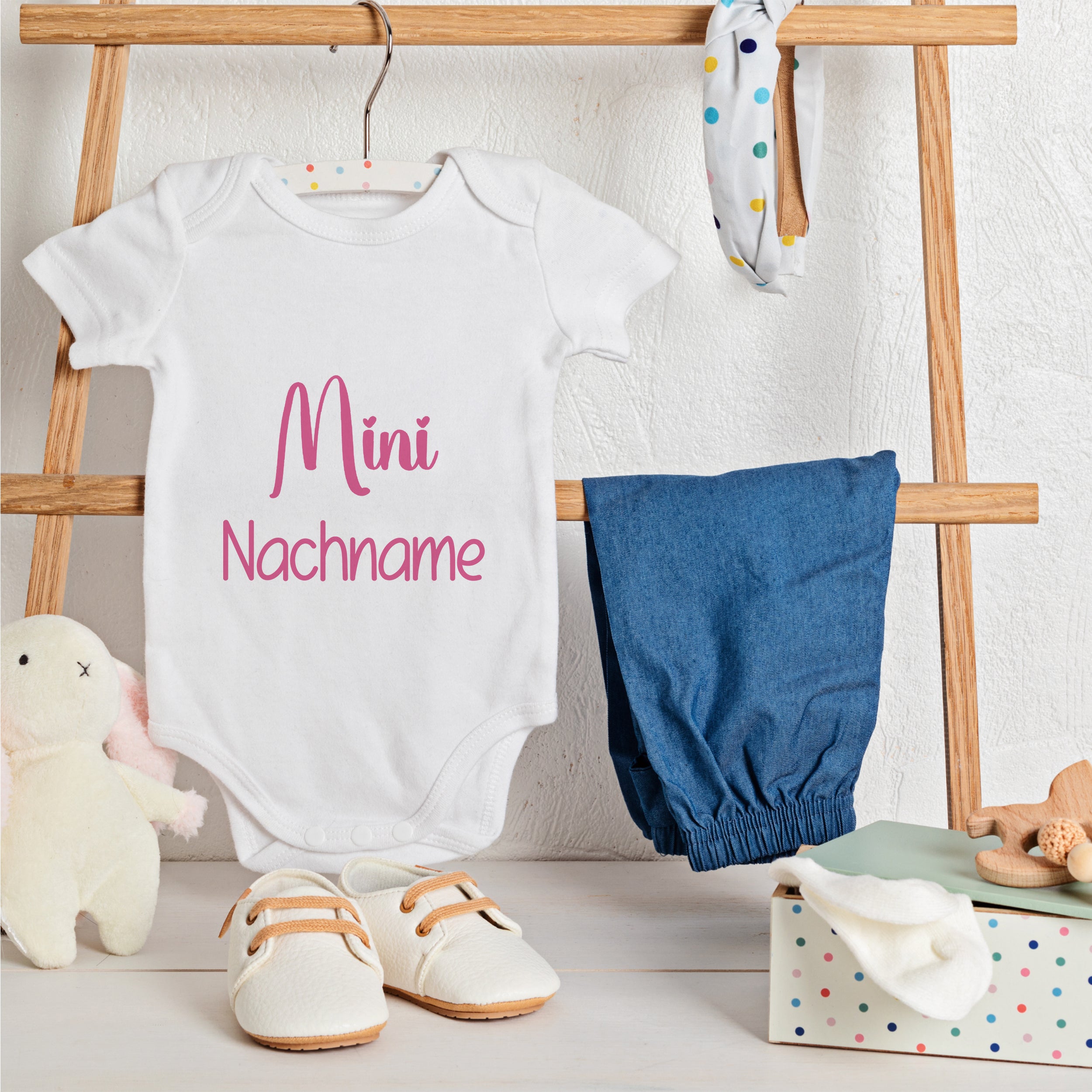 Weißer Babybody mit pinkem Aufdruck "Mini Nachname".