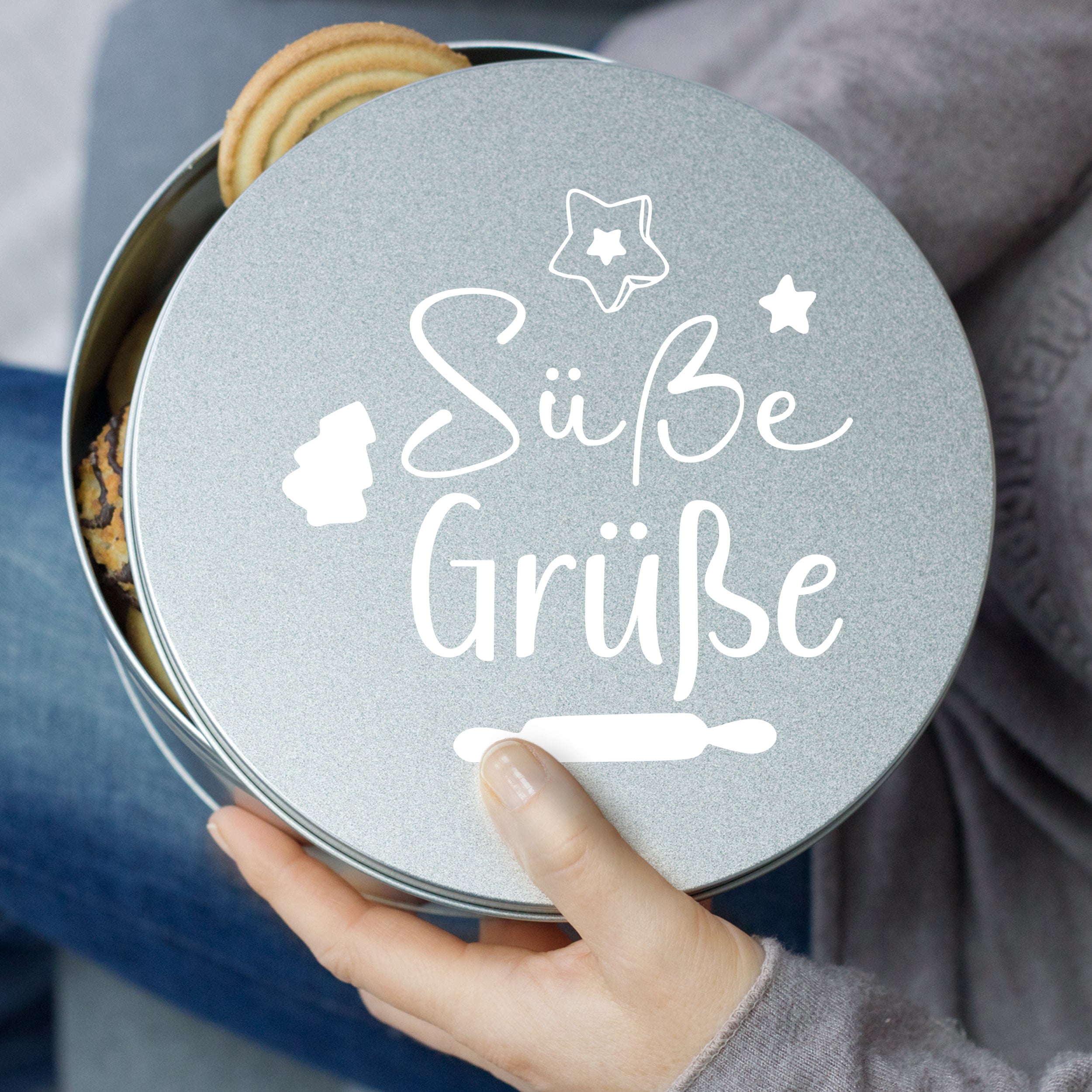 Silberne Keksdose mit Aufschrift "Süße Grüße" und Plätzchen.